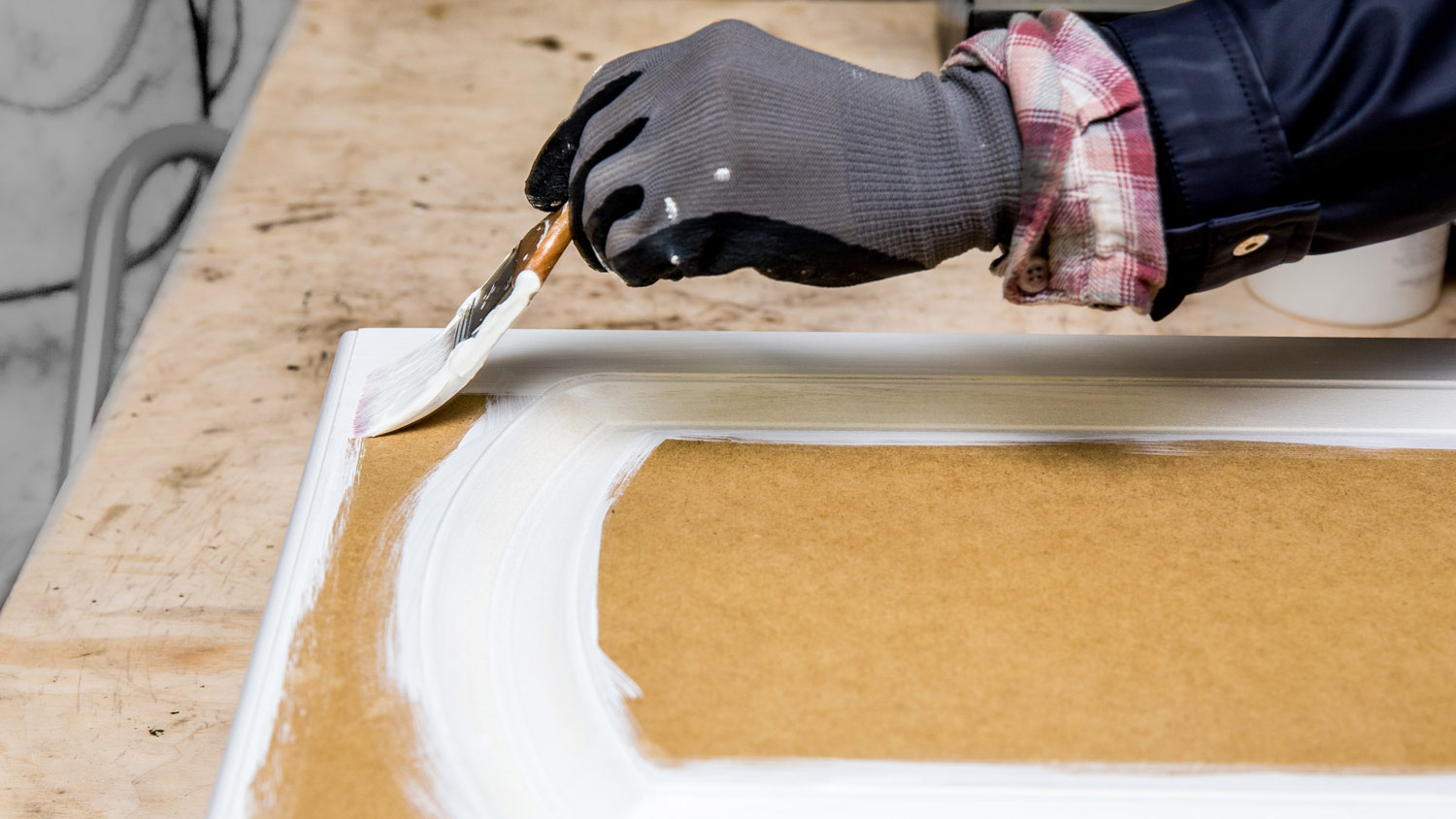 A hand painting a kitchen cabinet