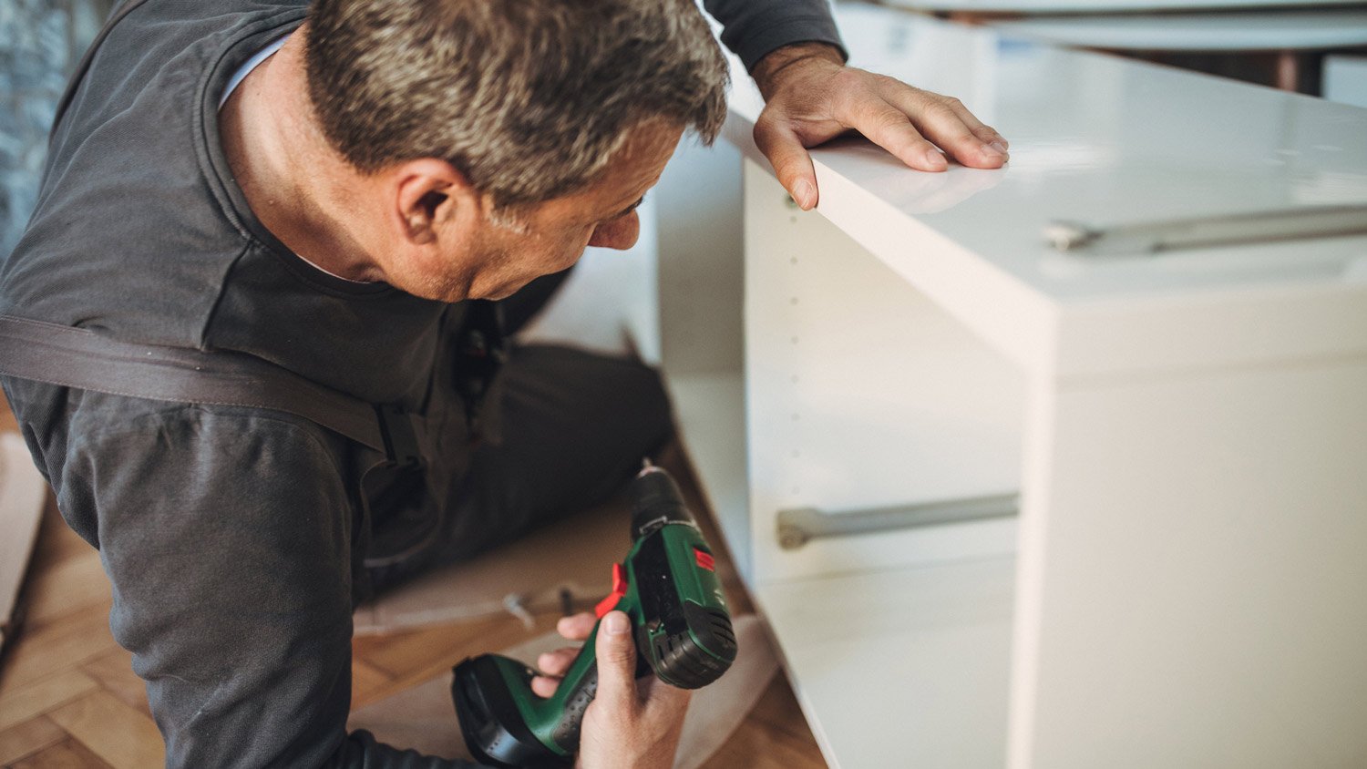 A handyman assembling furniture with cordless screwdriver