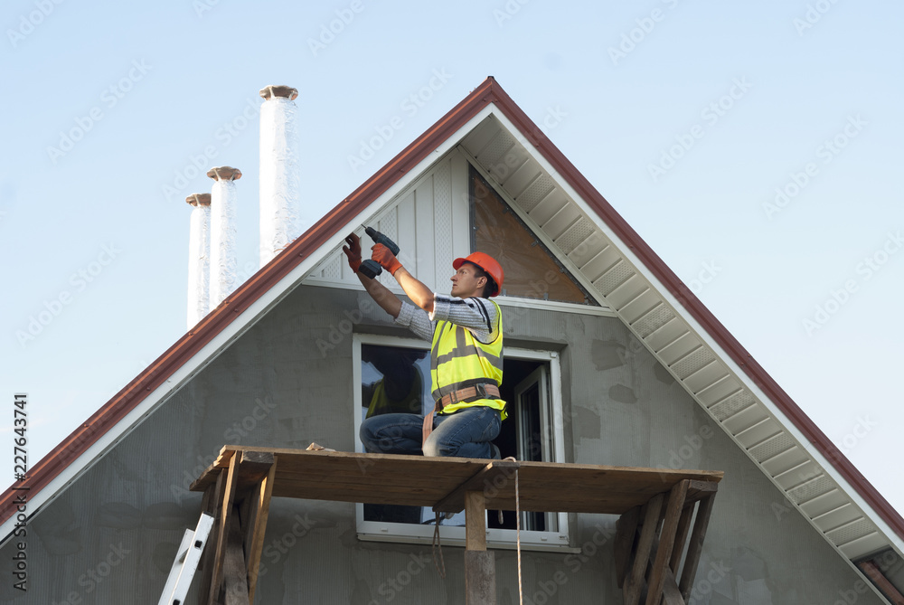 Worker on a scaffold installing new soffits