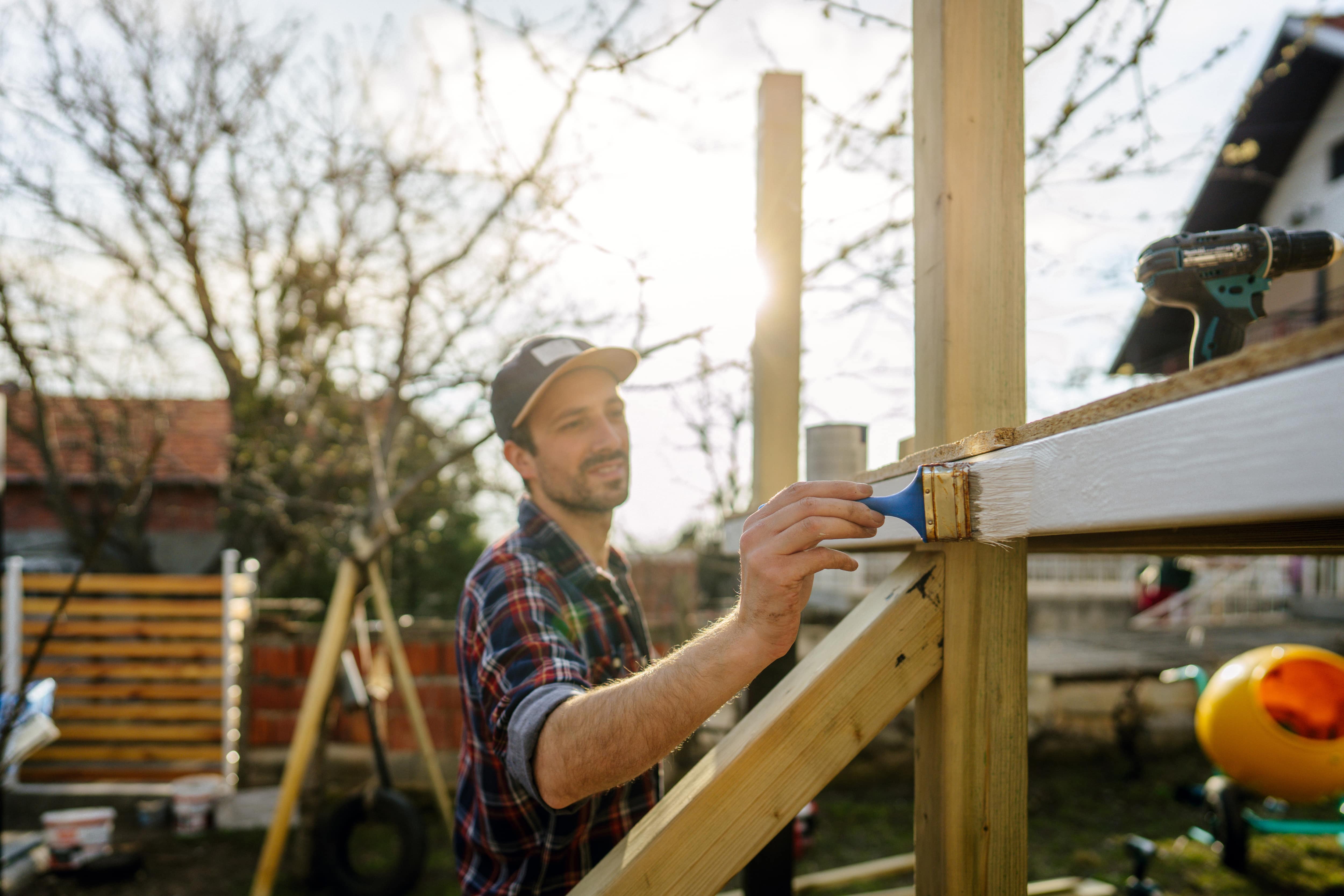 A man painting a treehouse exterior with white paint