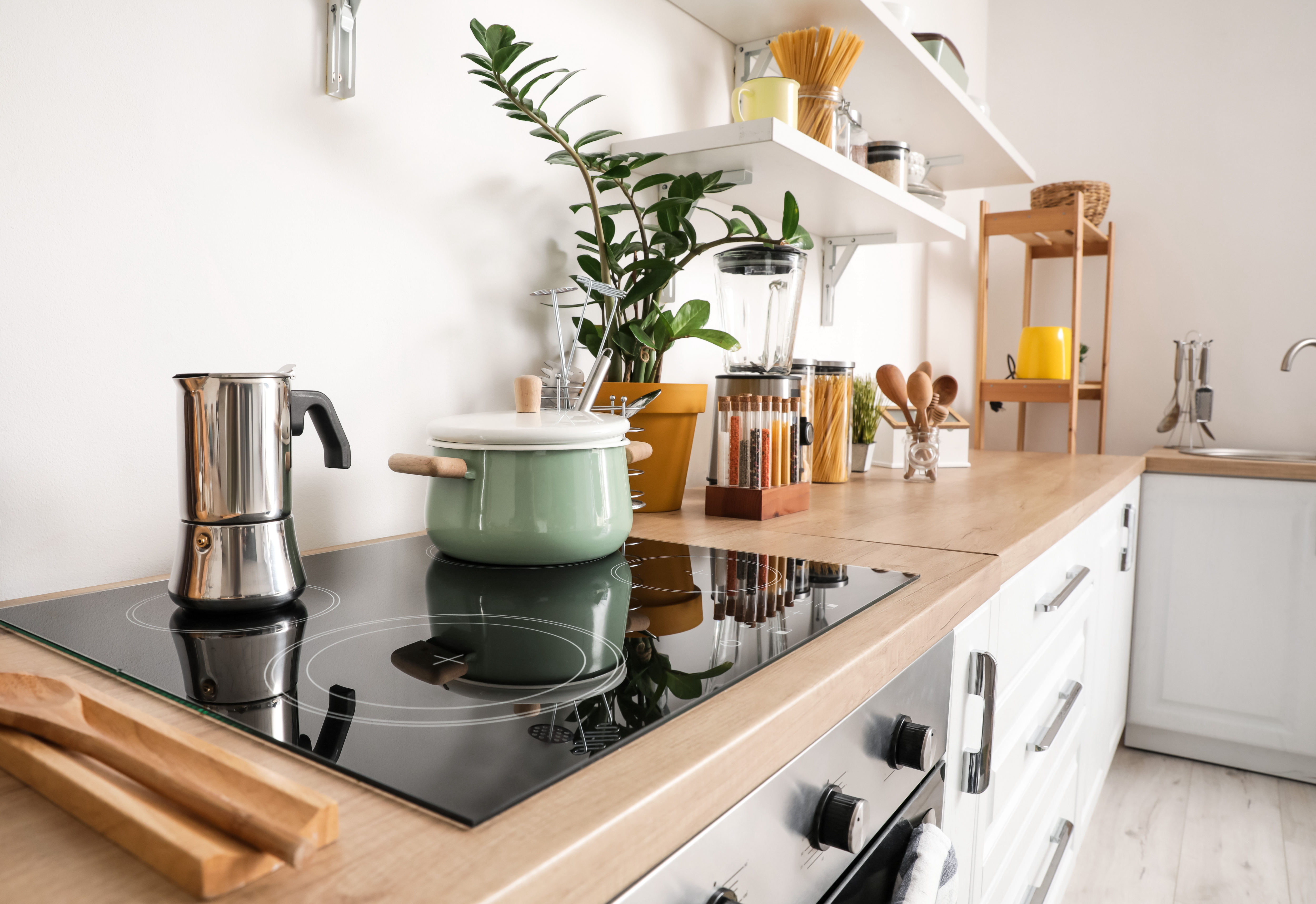 Electric glass stovetop with coffee maker and green pot sitting on top 