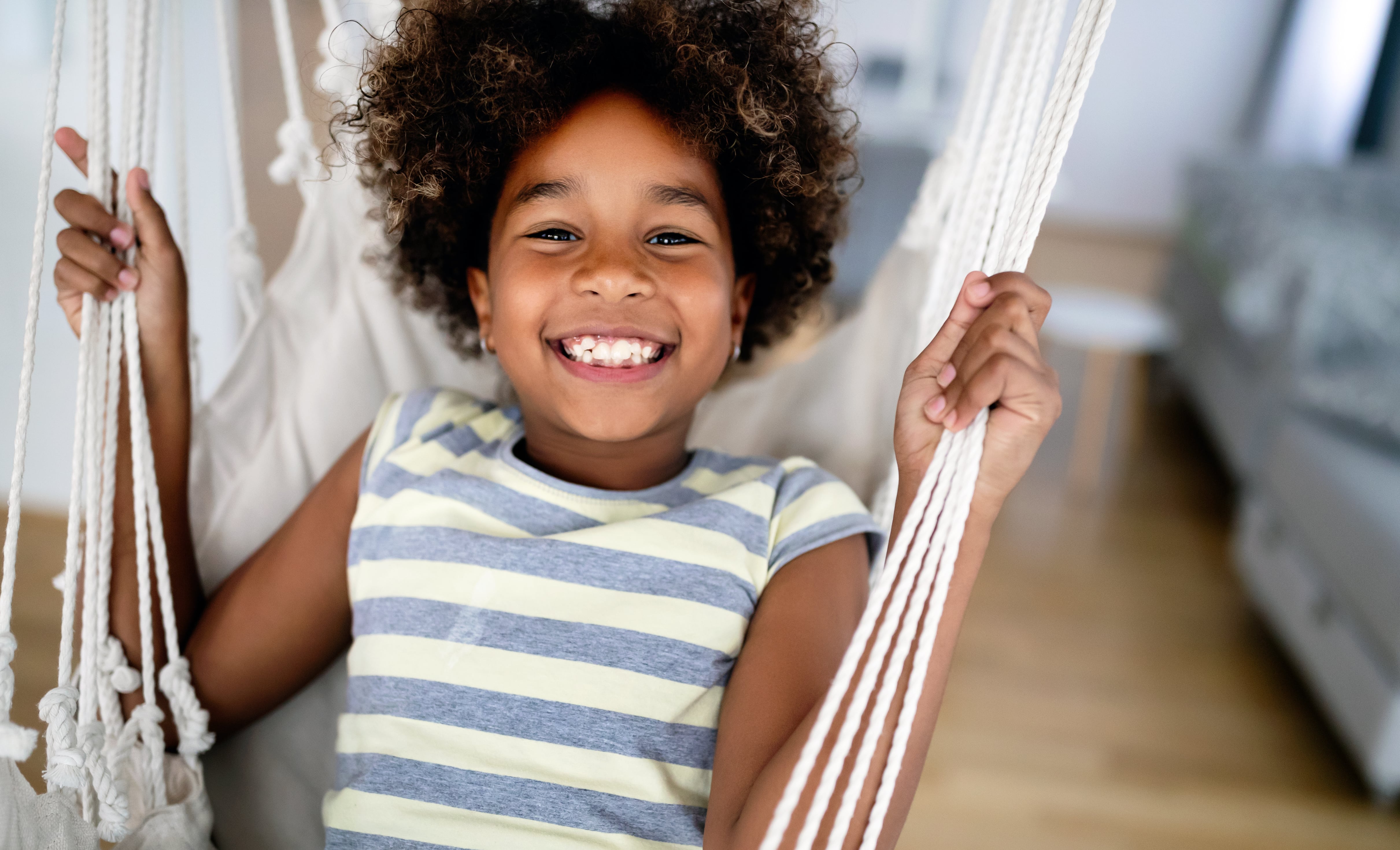 A young girl on an indoor hammock swing