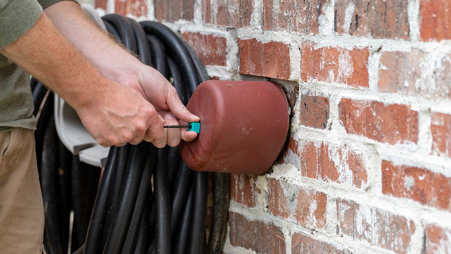 Hand installing outdoor faucet cover