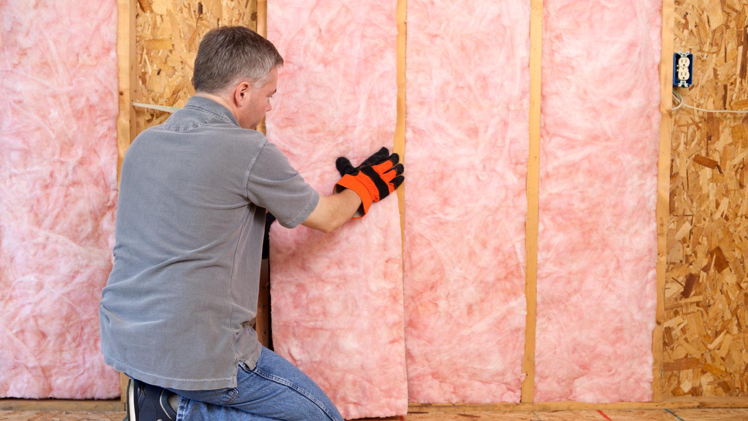 A worker installing fiberglass Insulation