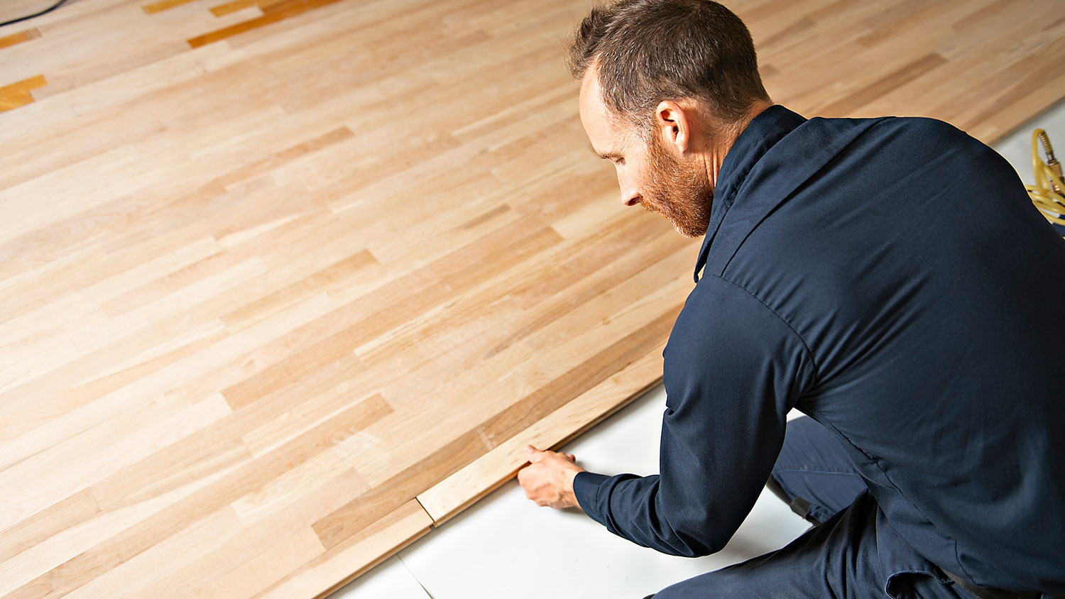 Handyman on his knees installing hardwood flooring