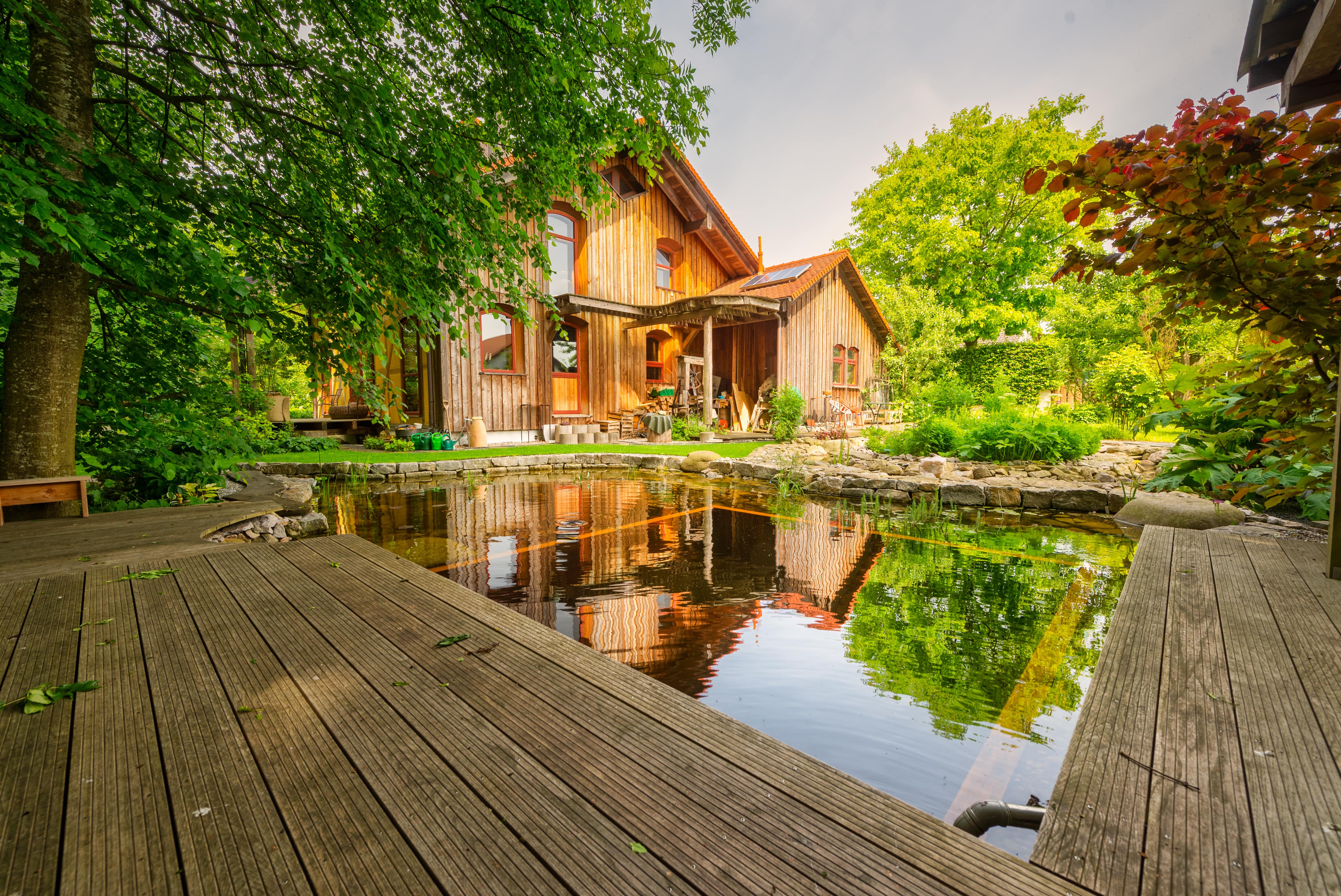 A square pond in a backyard surrounded in the middle of a wood deck