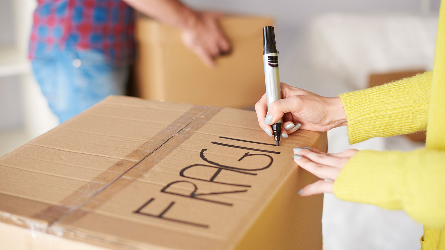 Closeup of a woman labeling carboard box with a marker