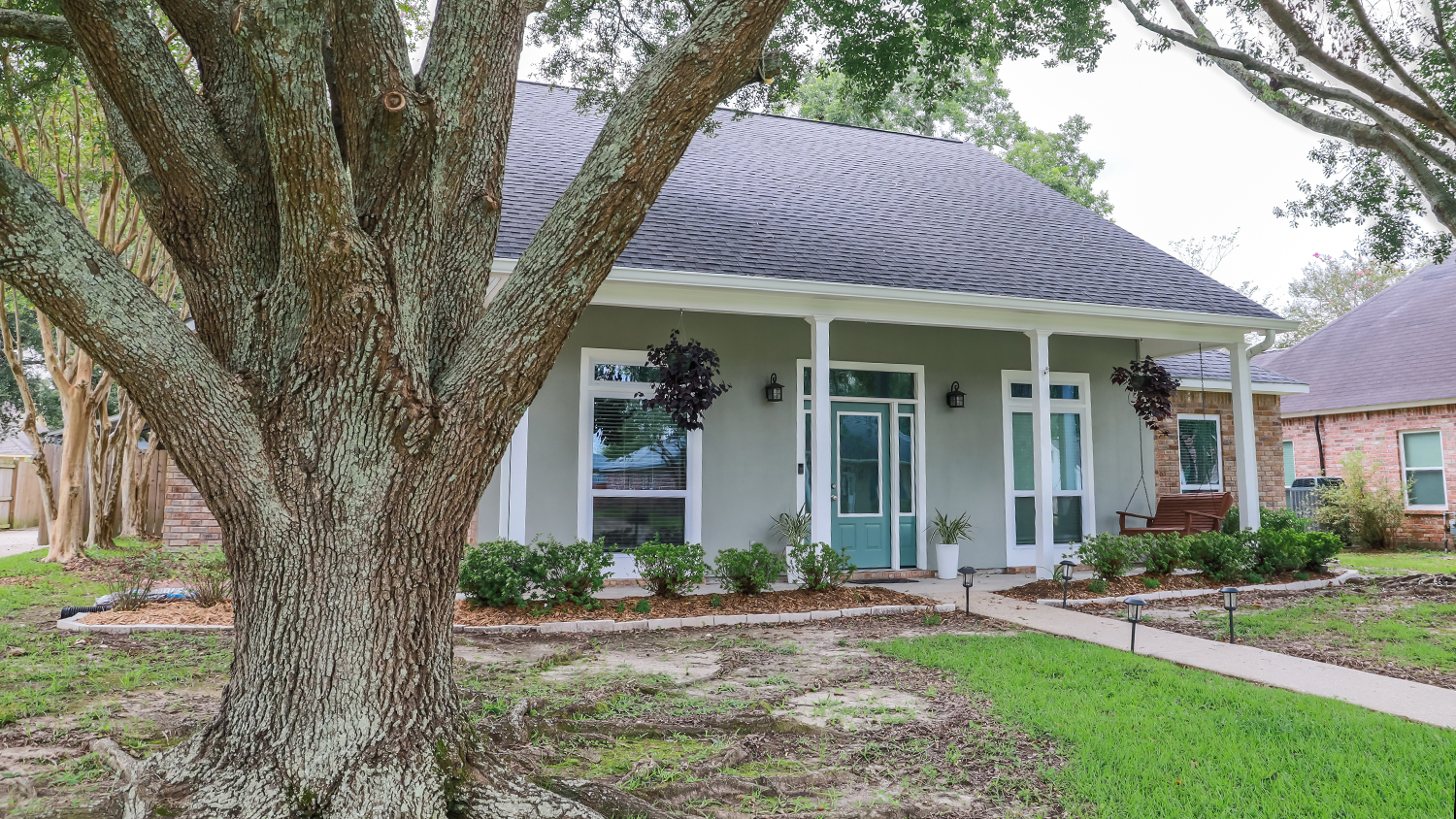 large tree in front of grey home