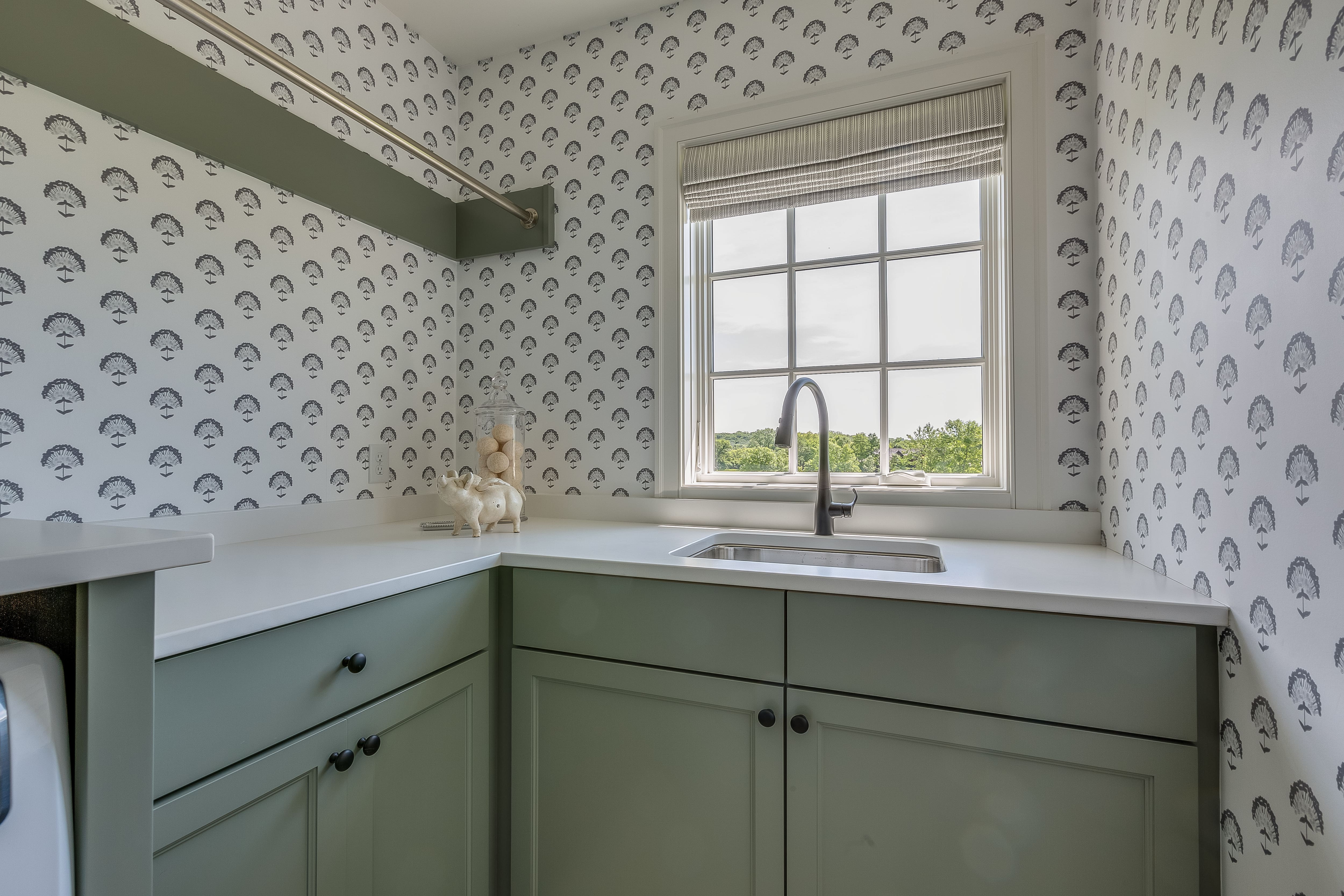 Wallpaper in laundry room with green cabinetry