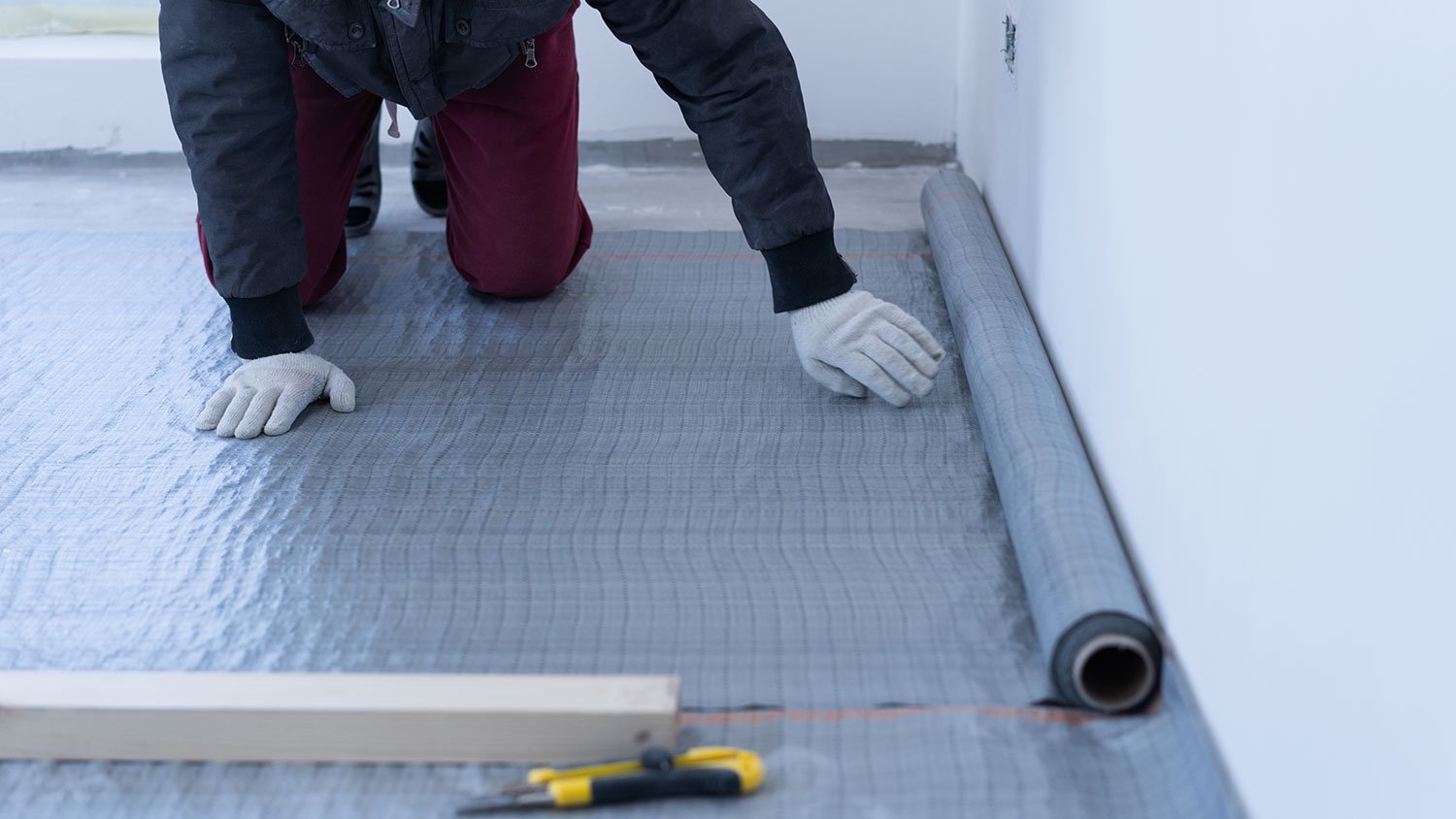 Worker laying vapor barrier on the floor