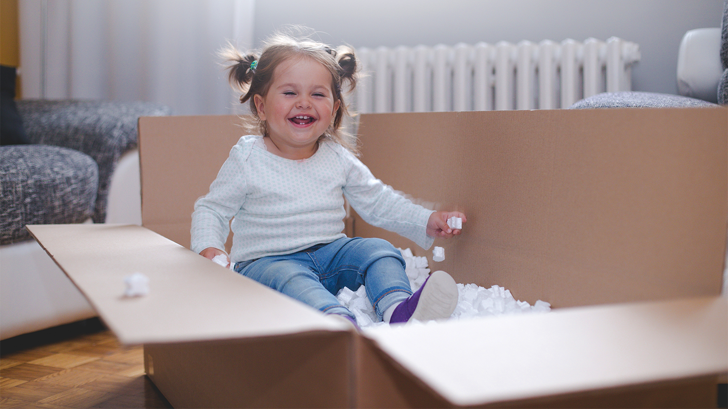 little baby girl playing in a box of foam pellets