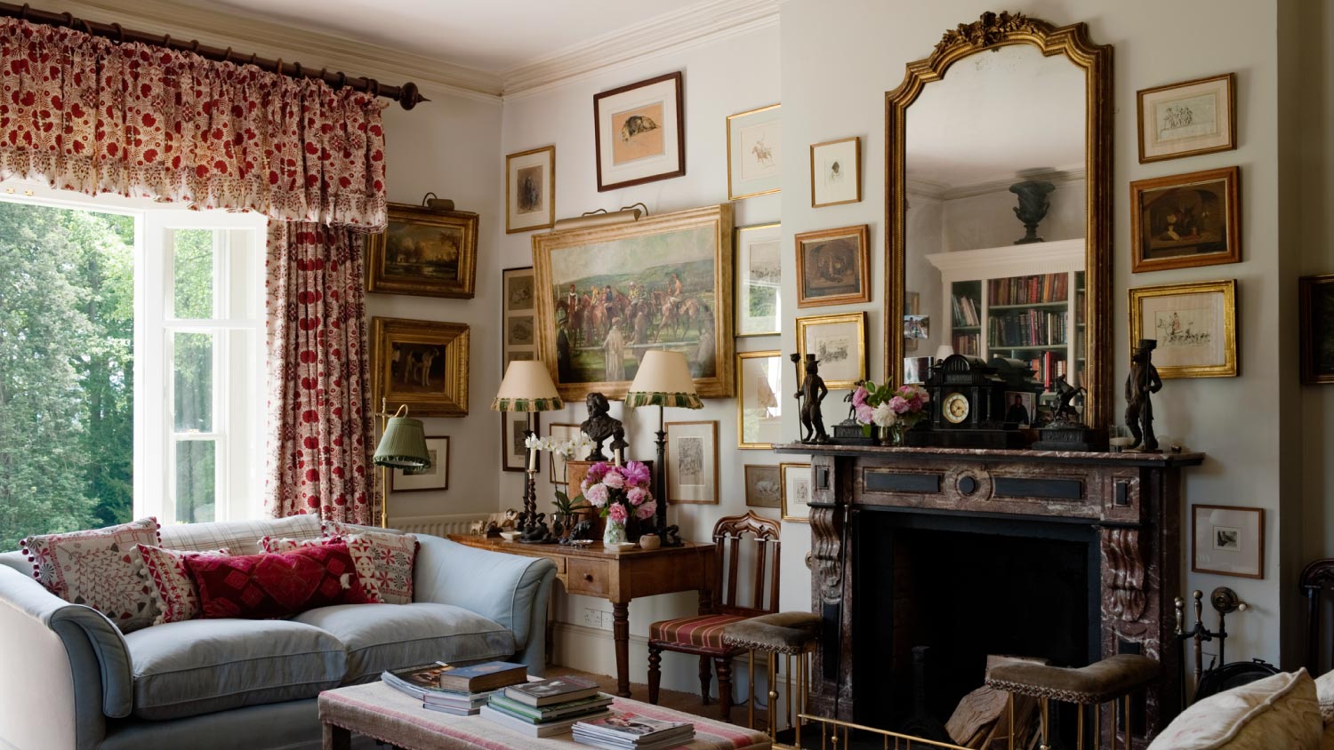 A living room with gilded mirror on fire mantle