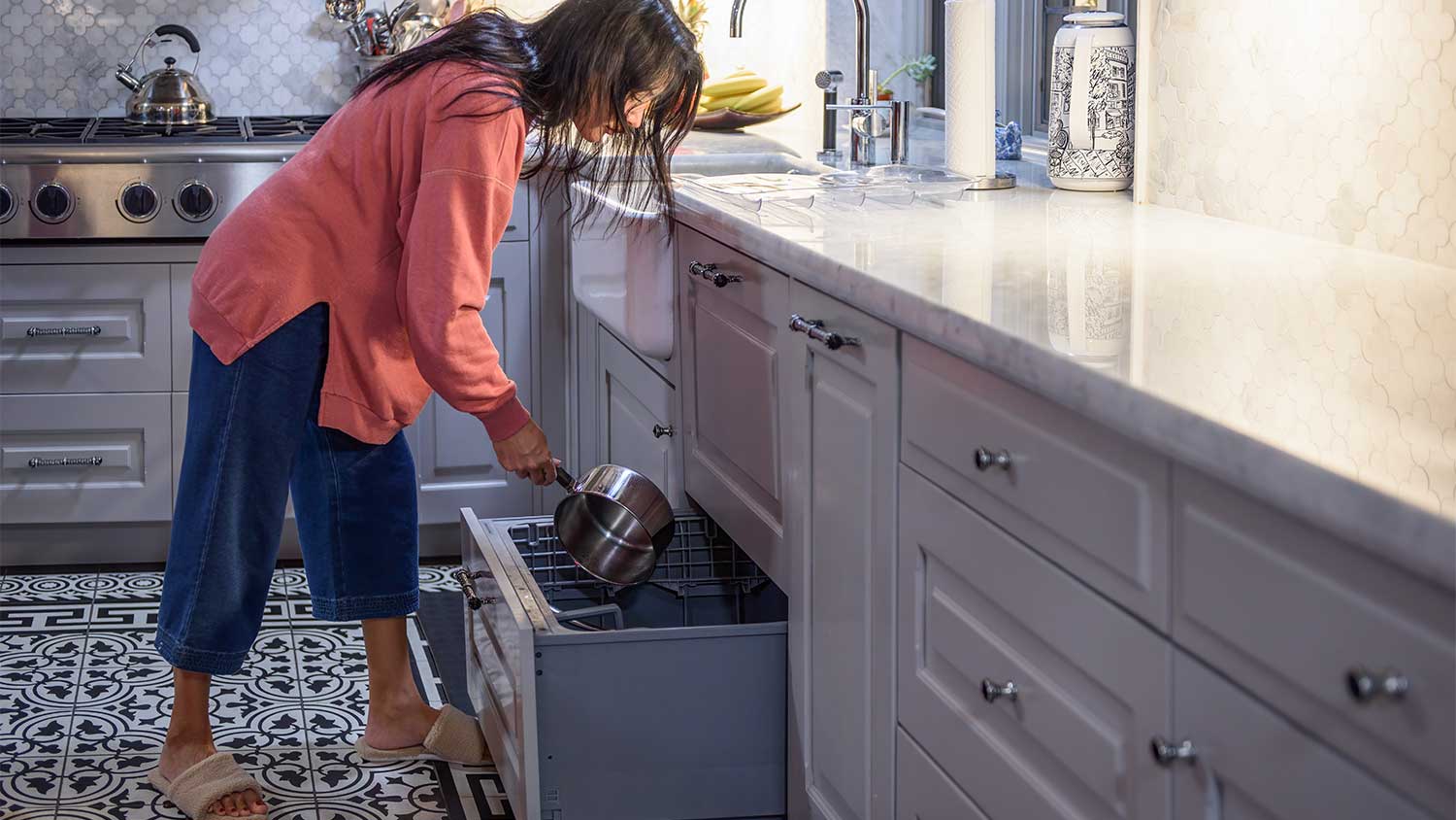 Woman loading a pot into a drawer dishwasher