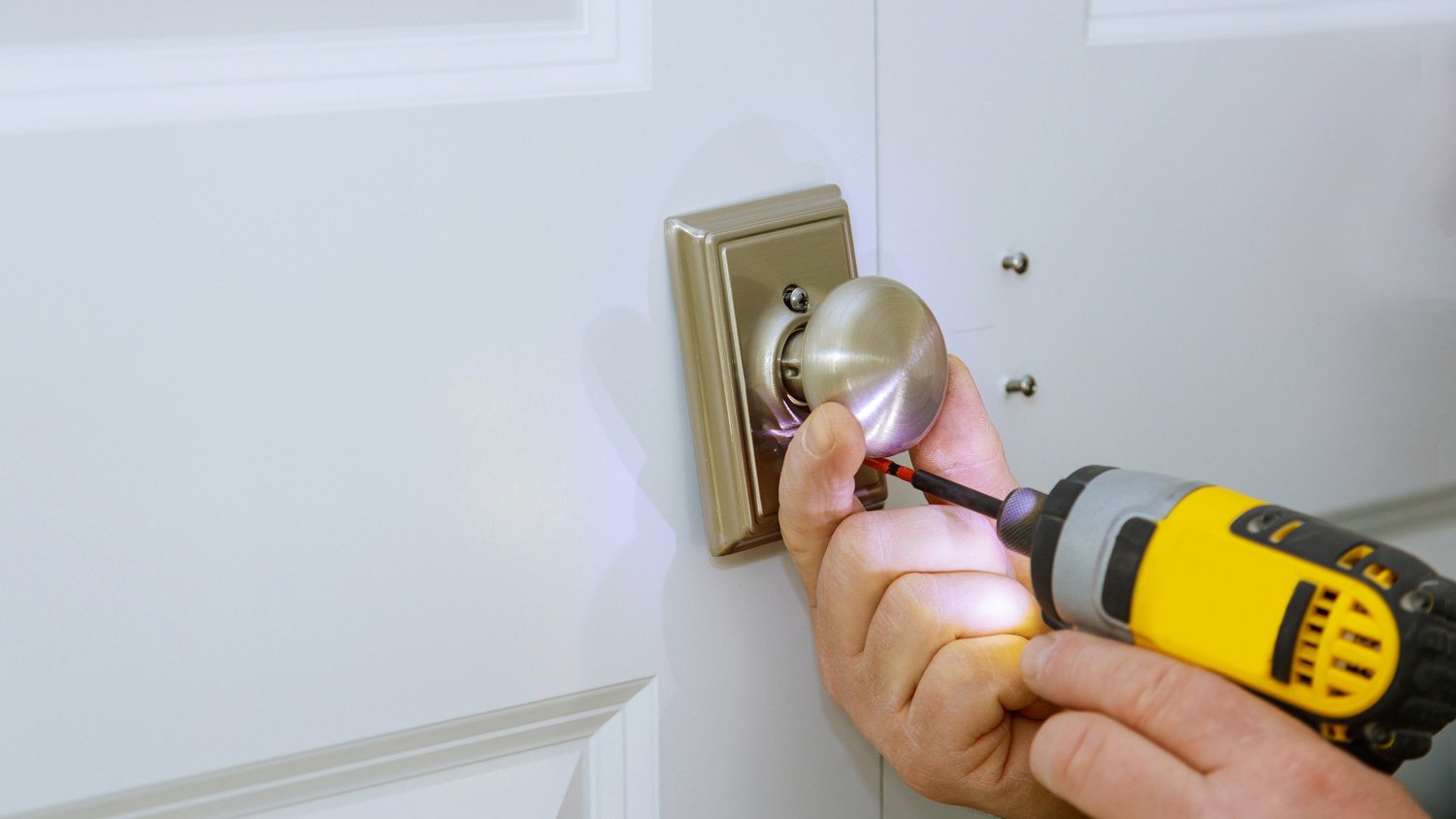 A locksmith using a screwdriver installing new dummy lock