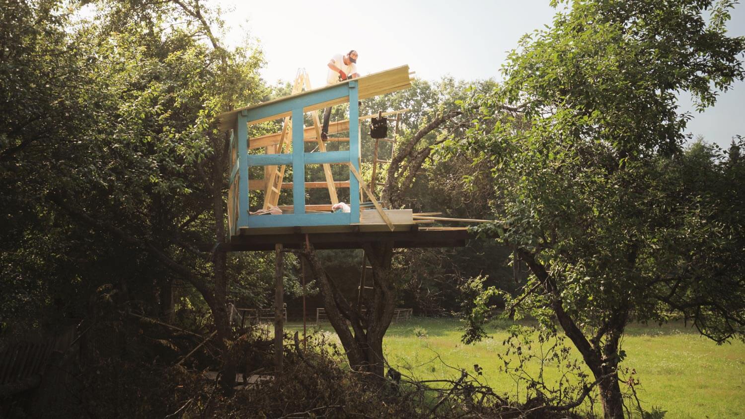 A man building a wooden treehouse