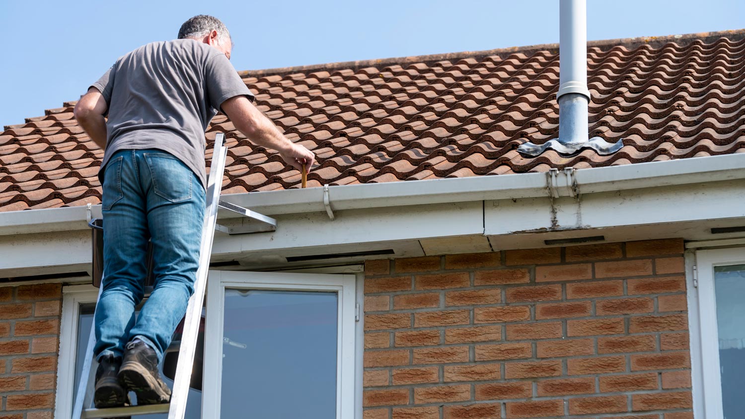 man cleaning leaves from gutter