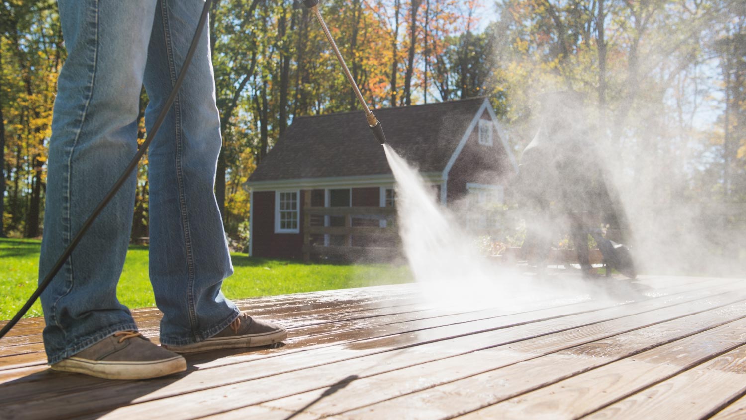A man cleaning porch with a pressure washing machine