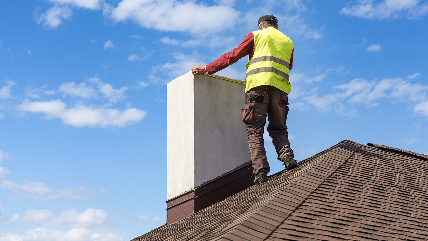 man on roof inspecting chimney