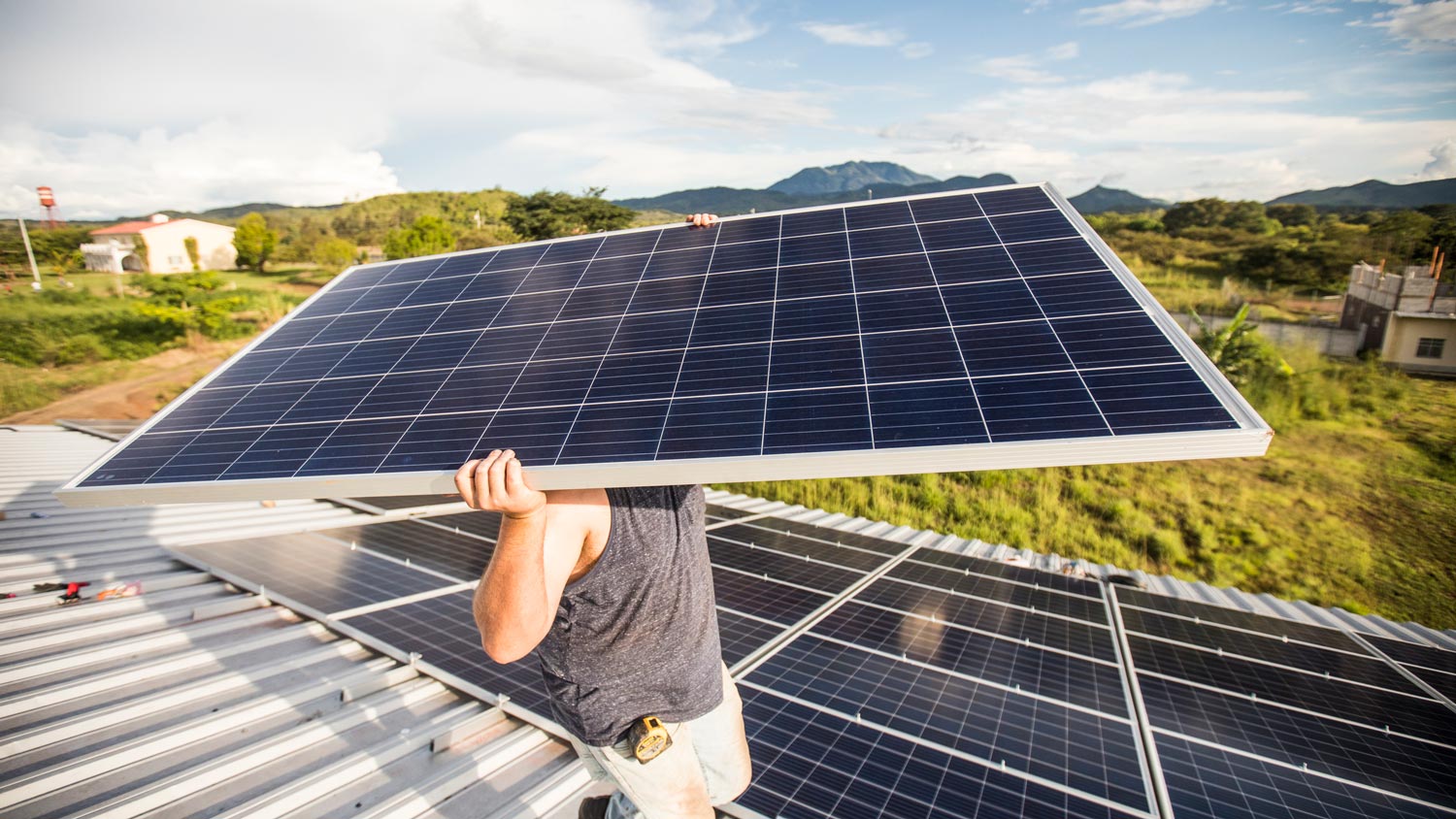 A man installing new solar panels on a roof