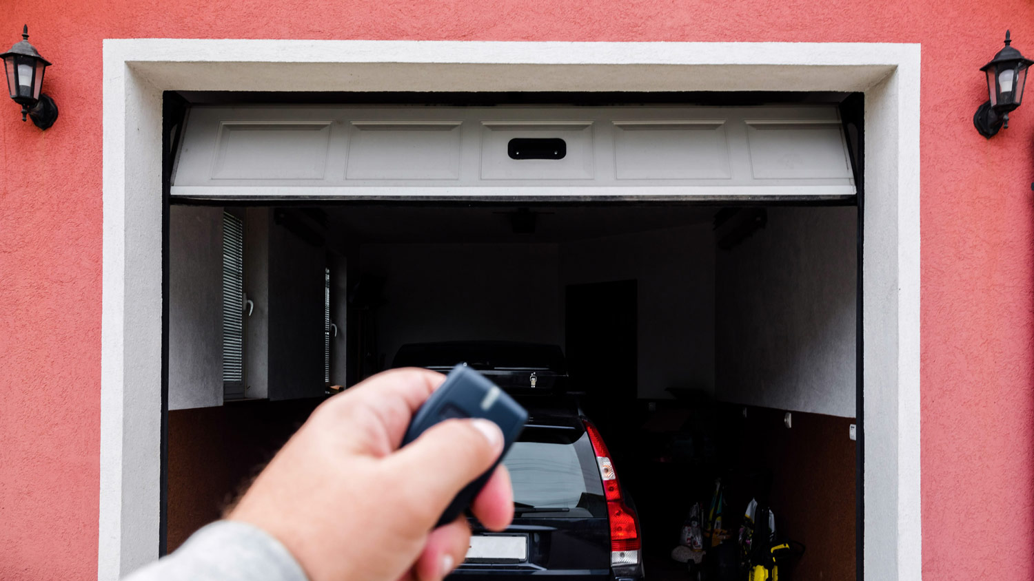 A man’s hand opening a garage door with a remote