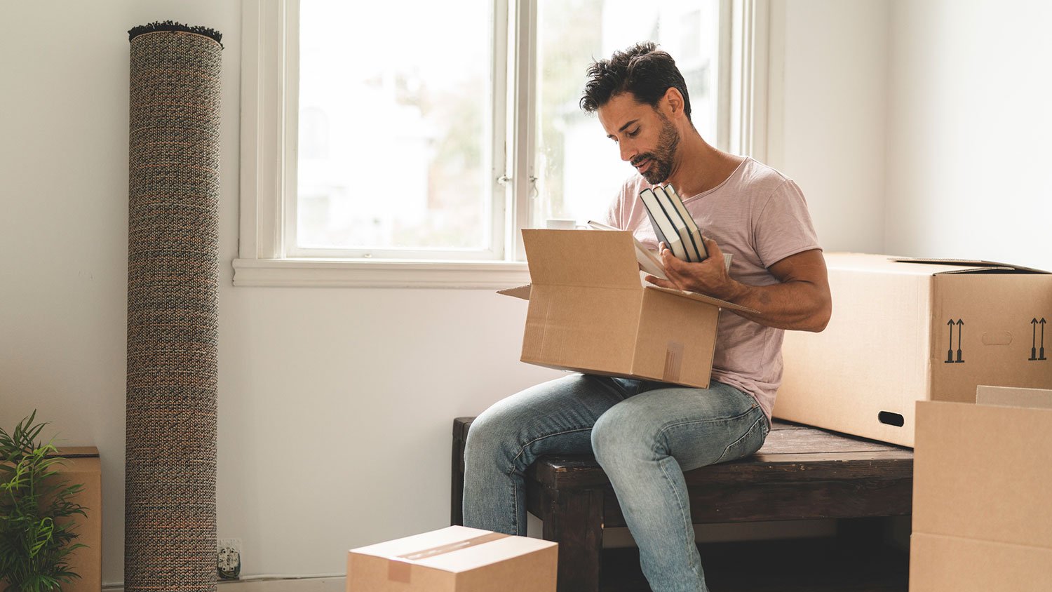 Man sitting on a table packing books in a box