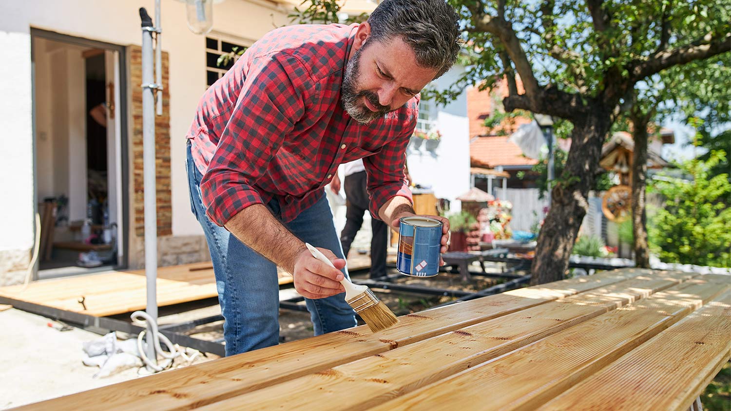 Man painting wood in yard