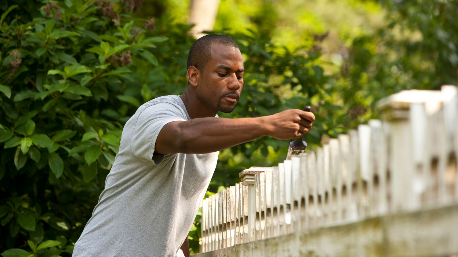 A man painting a picket fence