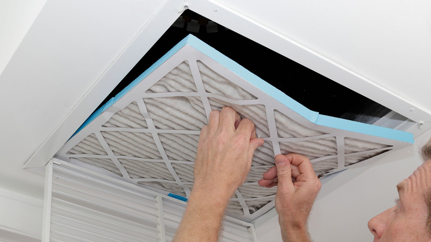 A man removing the air filter from an HVAC system