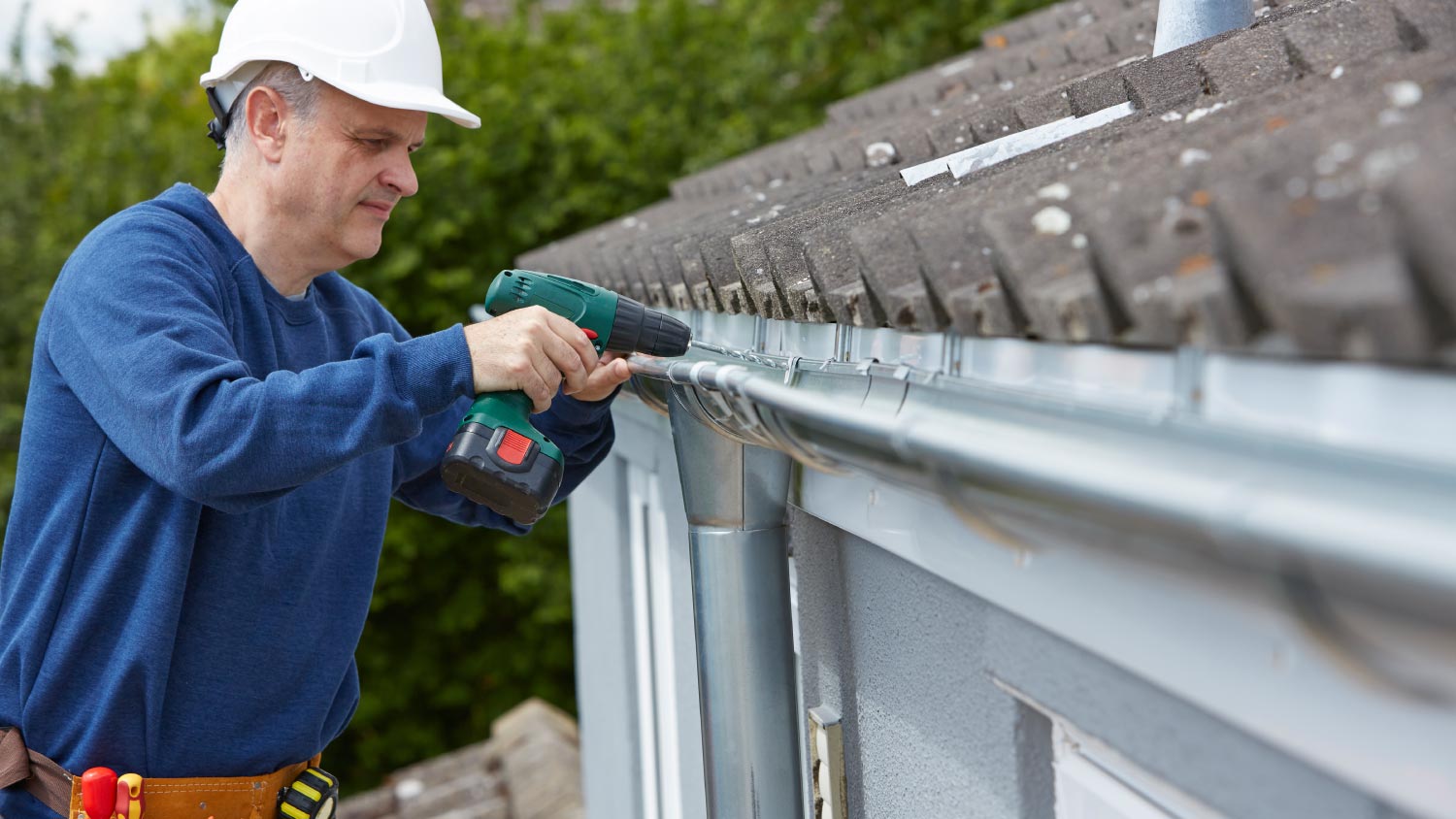 Man replacing guttering on exterior of house