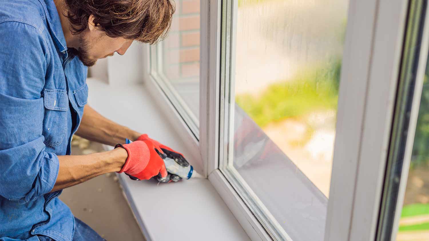 Man seals window frame