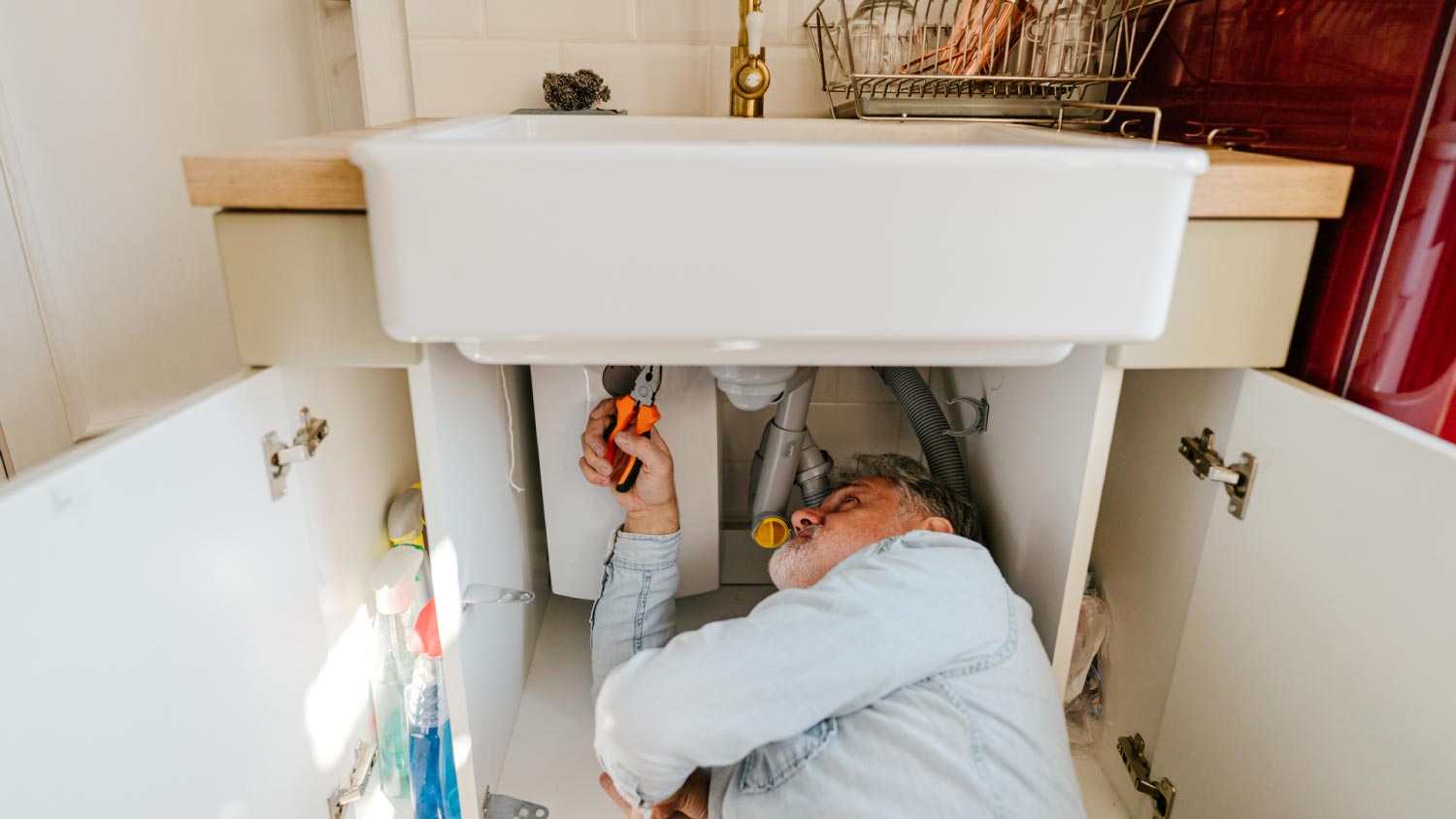 Man solving plumbing problems in a kitchen