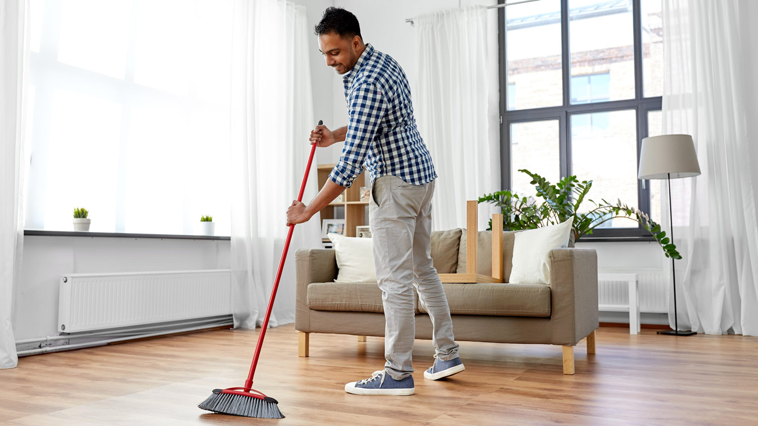 A man sweeping the floor in his living room