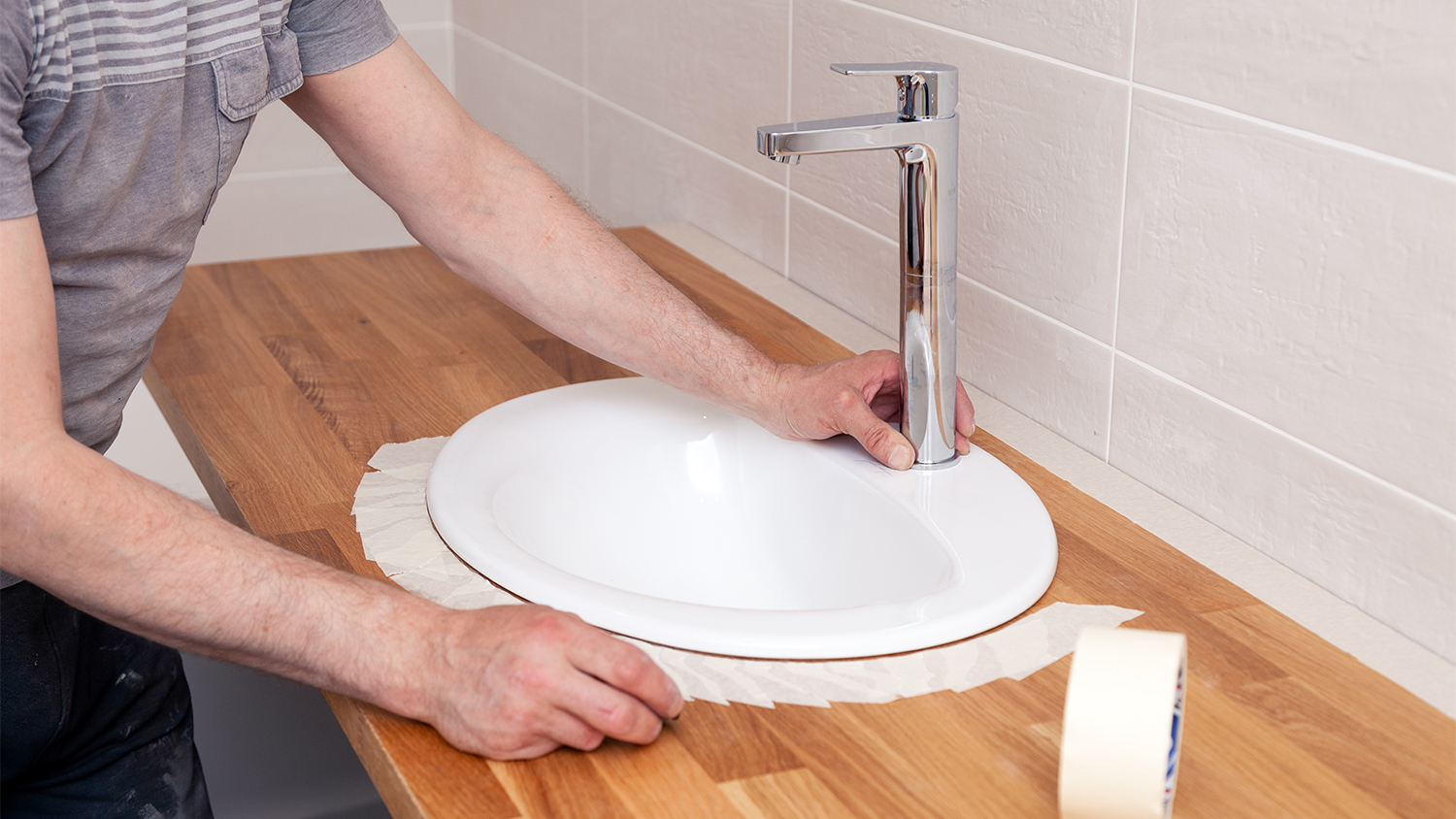man apply masking tape on sink