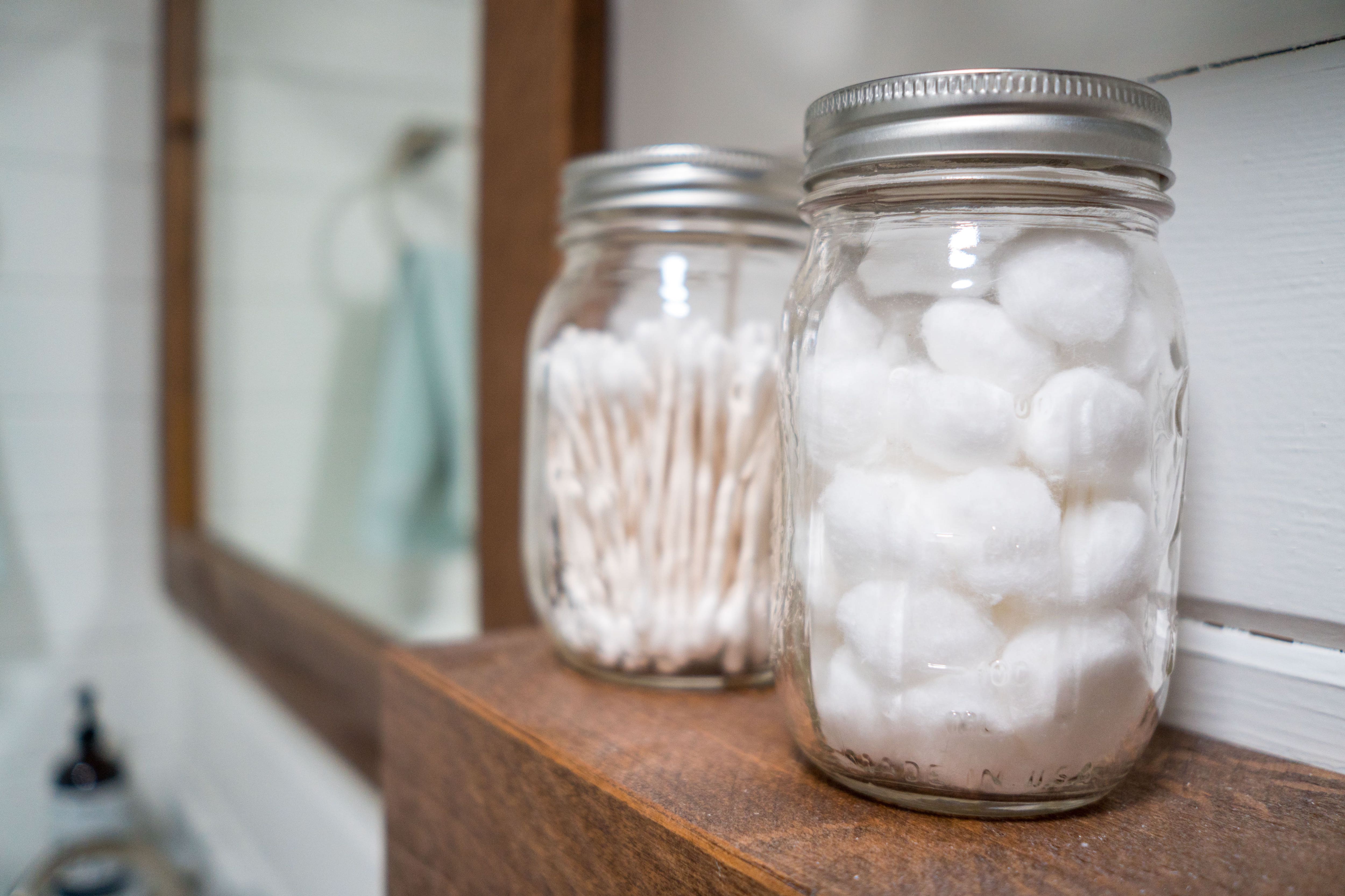 Cotton balls and cotton swabs stored in mason jars in bathroom