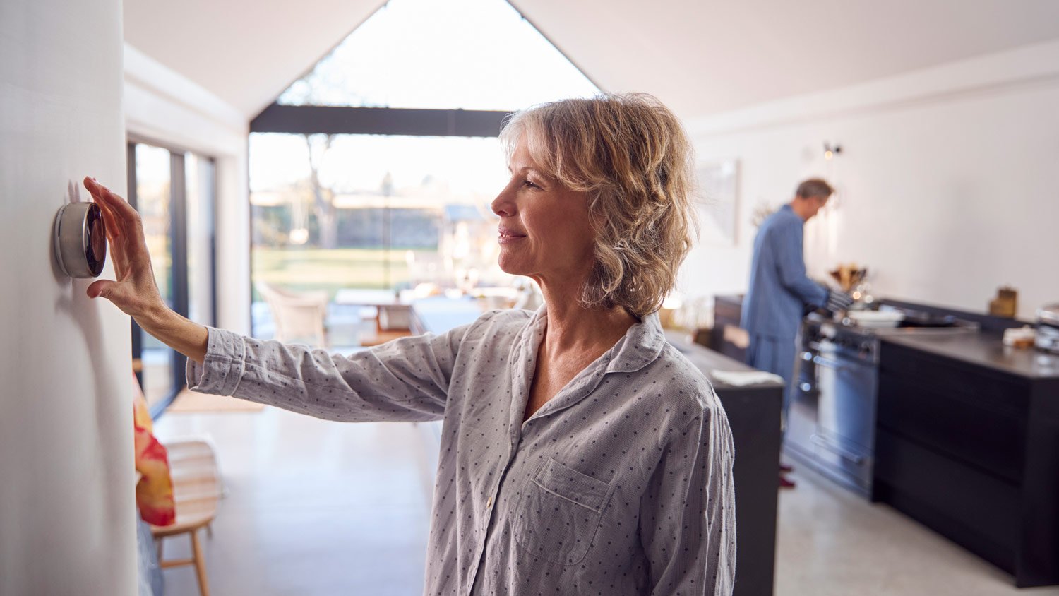 A mature woman adjusting a smart thermostat