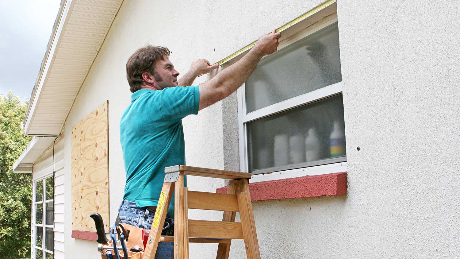 Worker measuring window frame