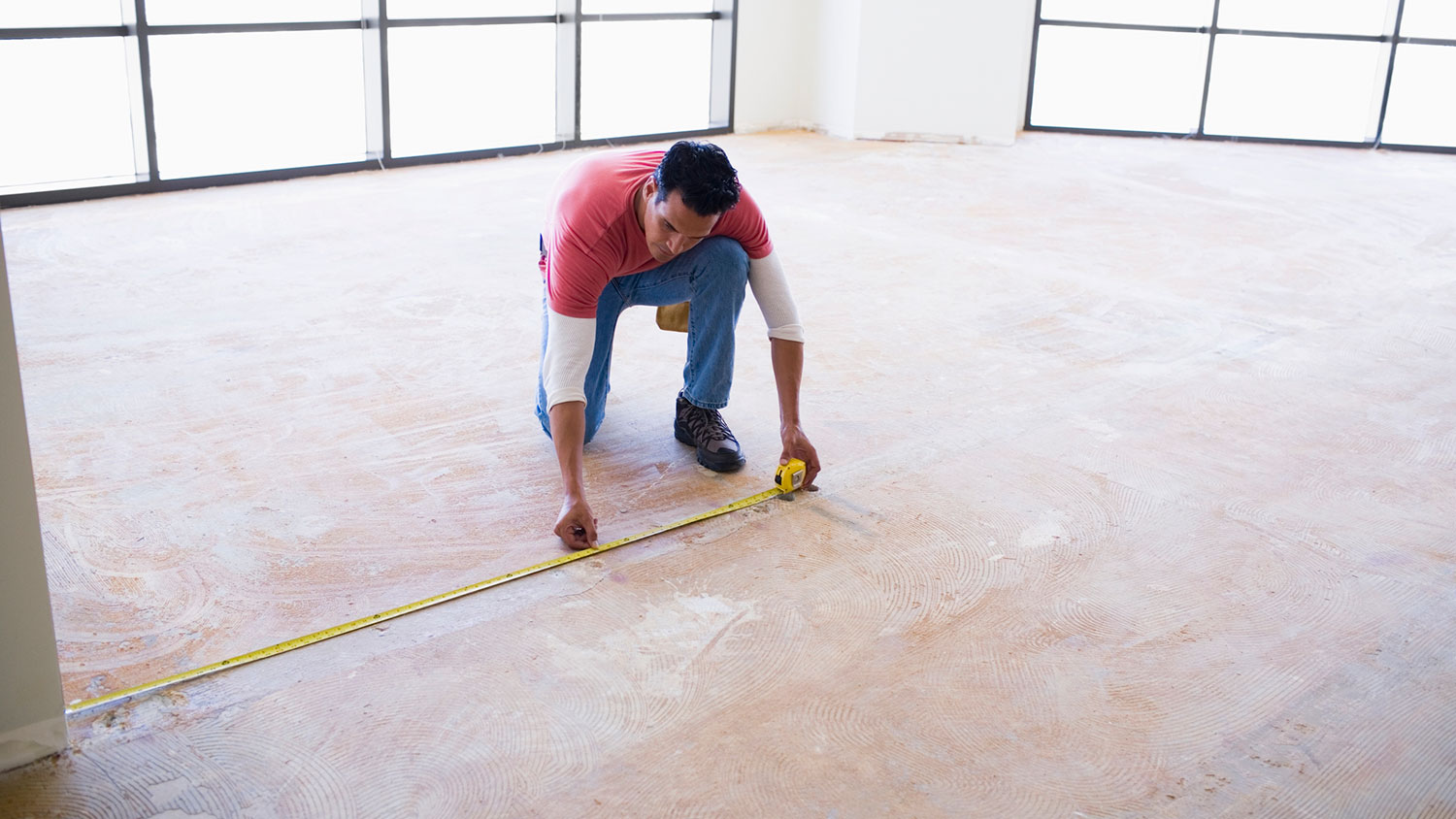 Man using measuring tape to measure floor space