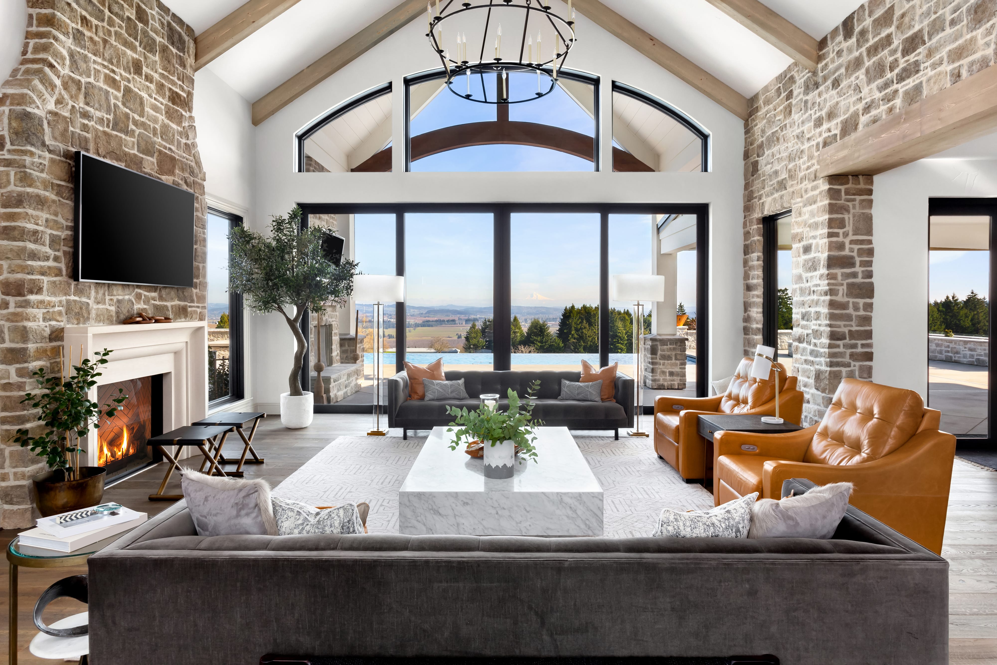 Large open-concept living room with industrial chandelier and stone walls