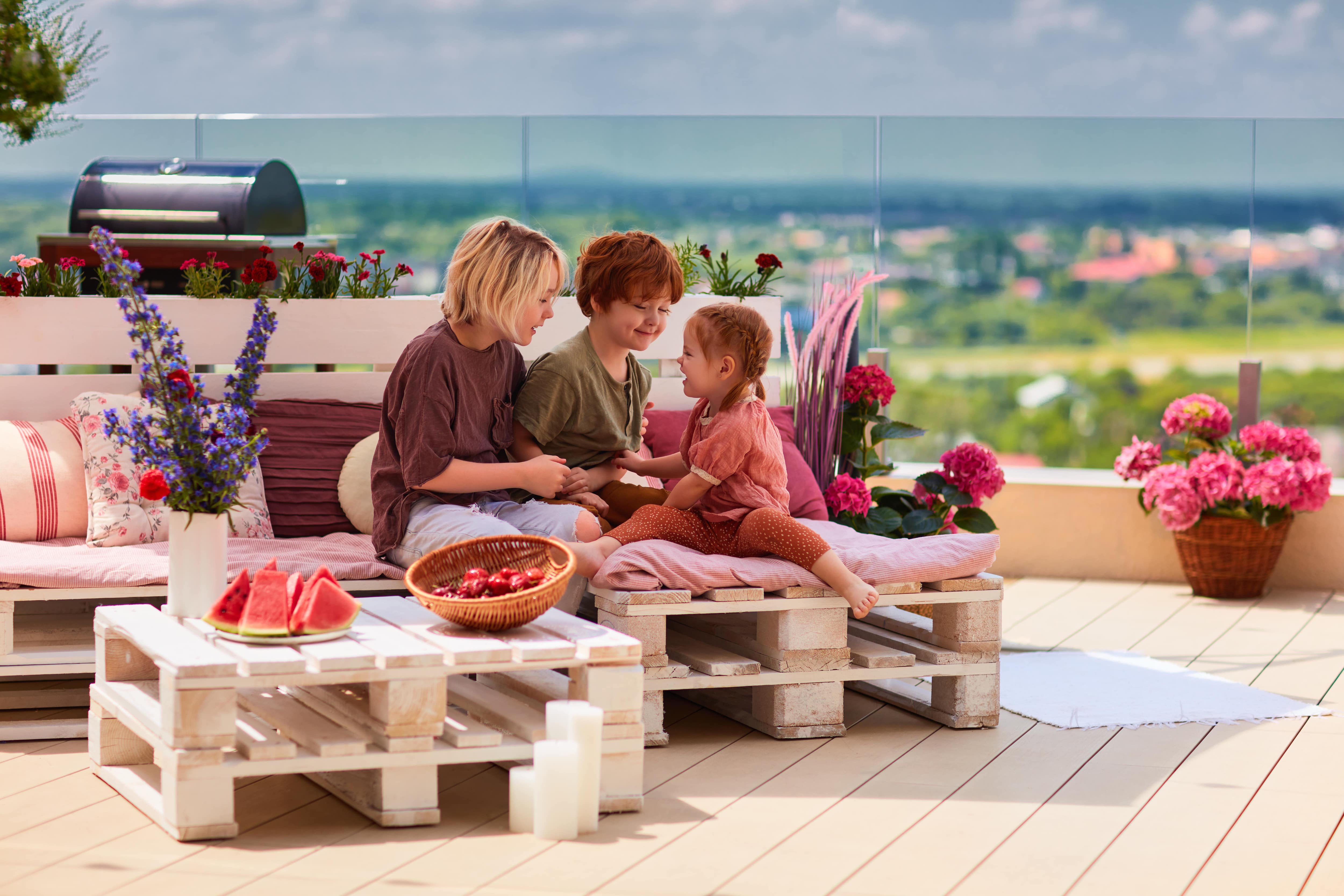 Three kids sitting on a modern outdoor patio made of composite decking materials