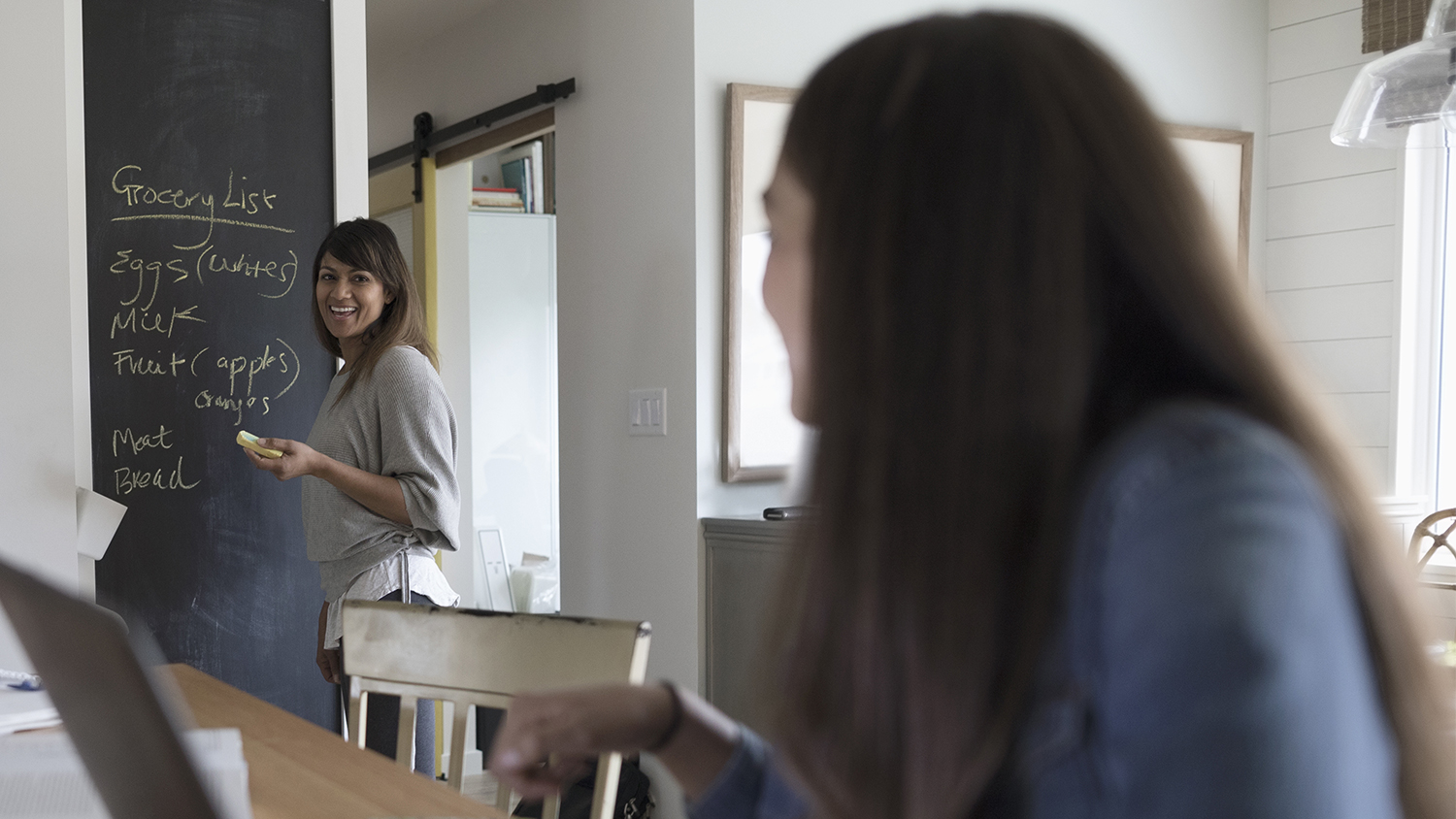 mom writing grocery list on chalkboard