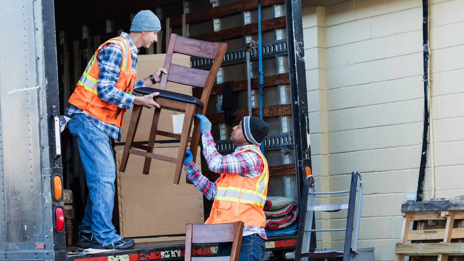 Two workers from a moving company unloading furniture from a truck
