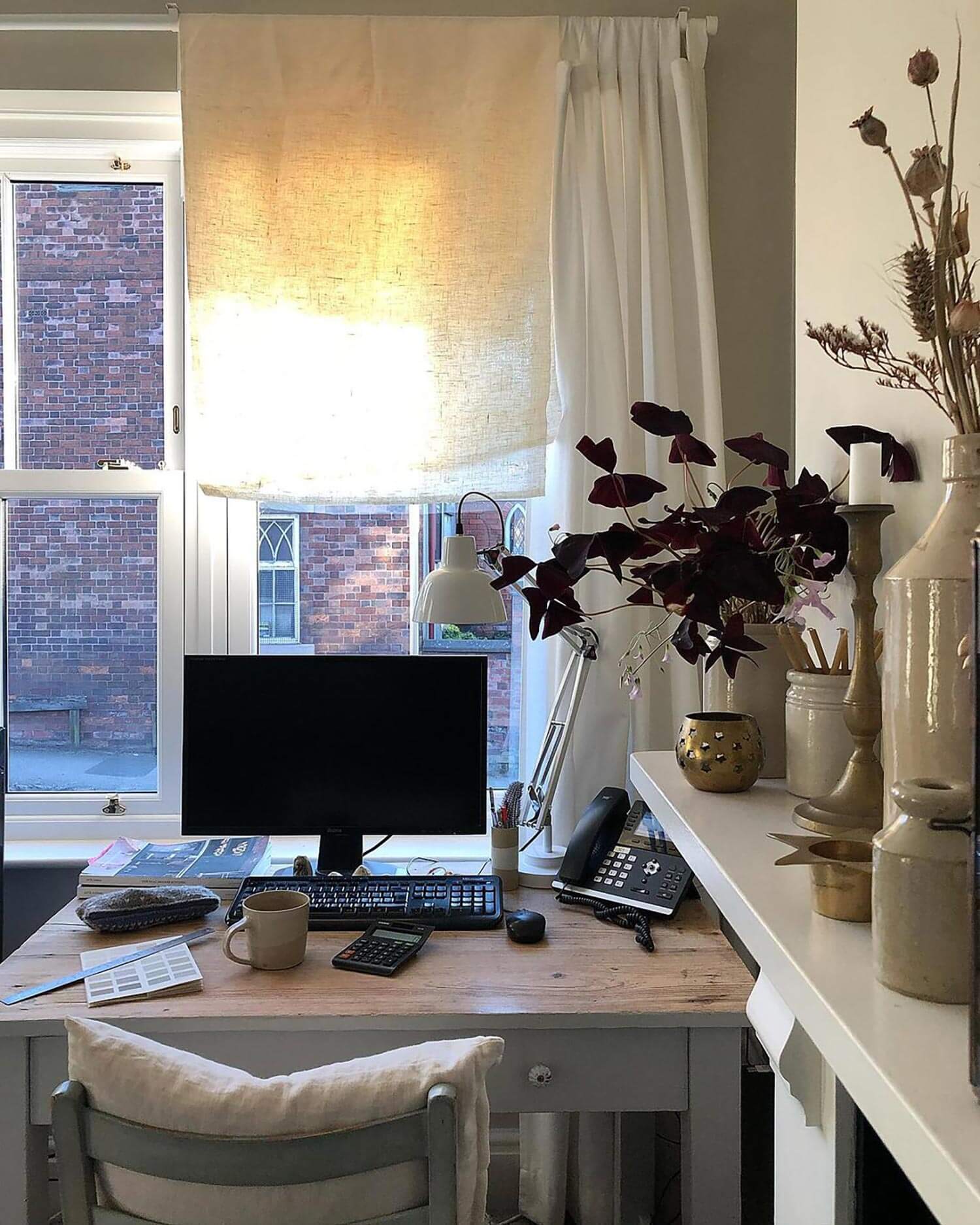 A home office with clay pots on the side and linen curtains