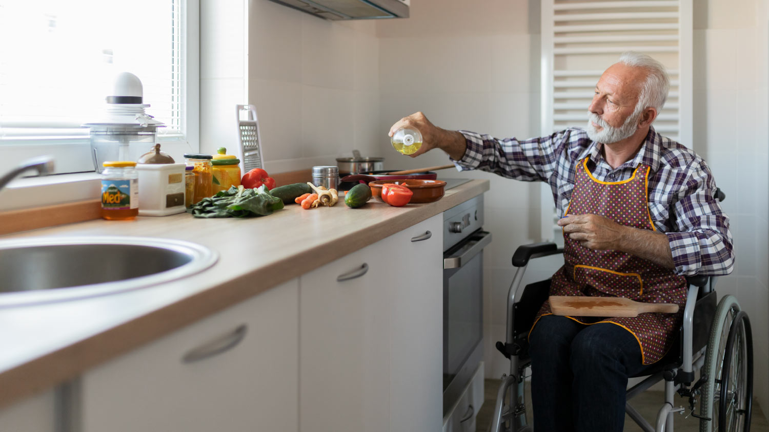 older man in wheelchair making food in kitchen