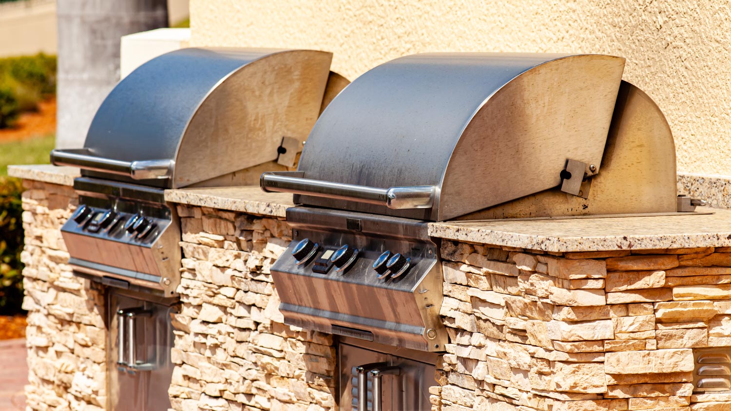 An outdoor kitchen with two grills mounted in a stone counter