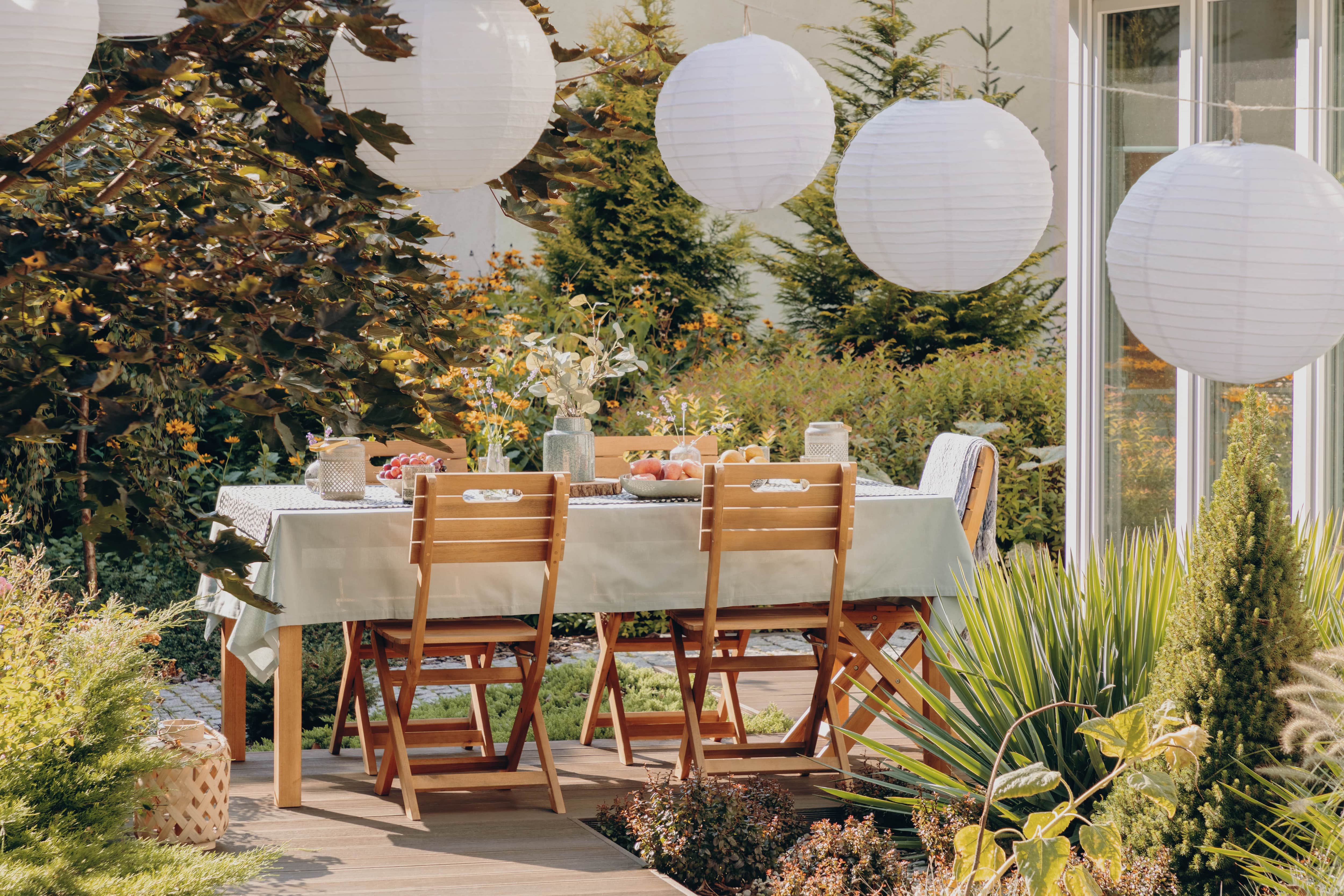 Patio with a table and chairs surrounded by white paper lanterns and tea candles