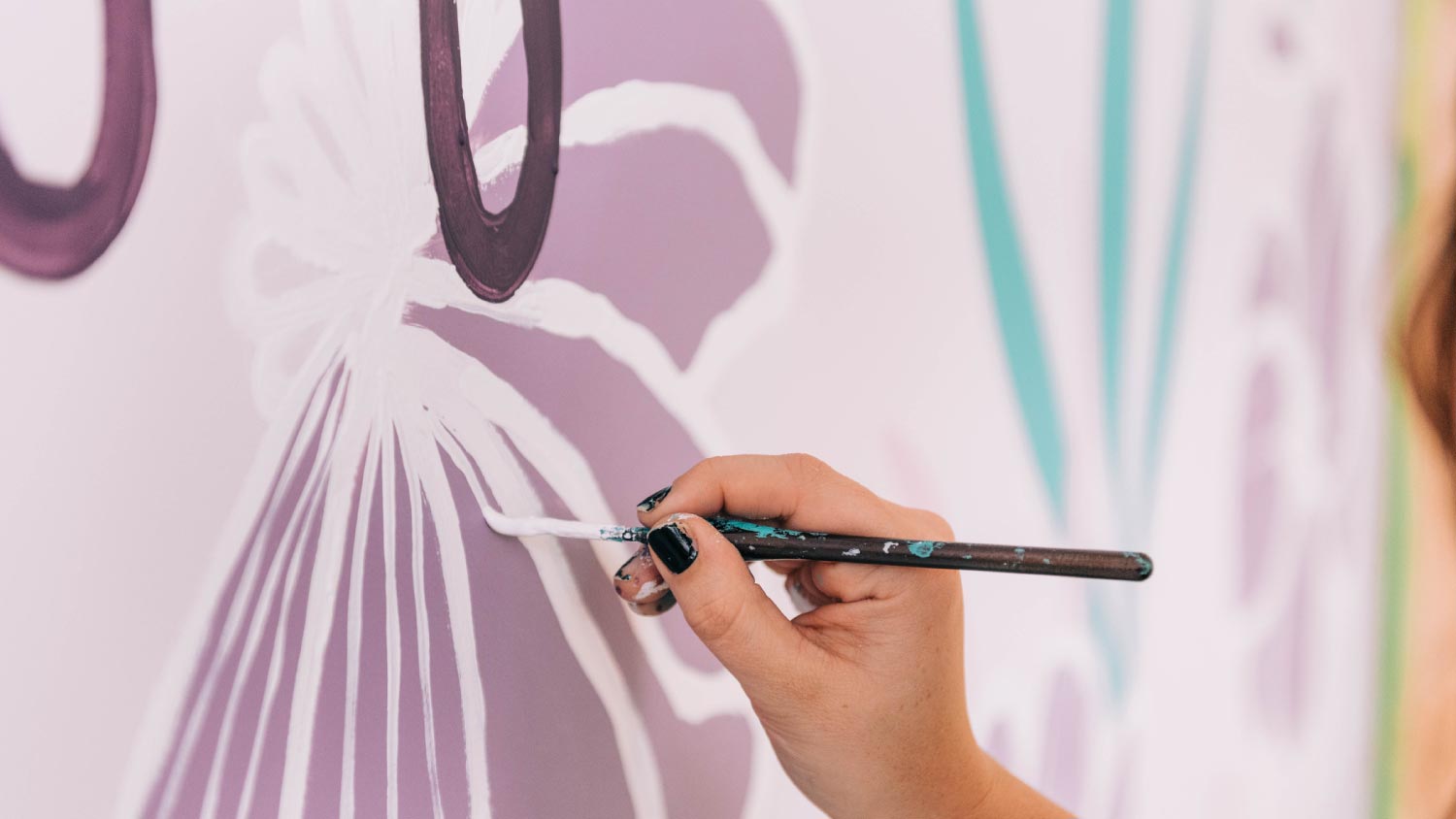 A close up of a painter painting florals on a wall