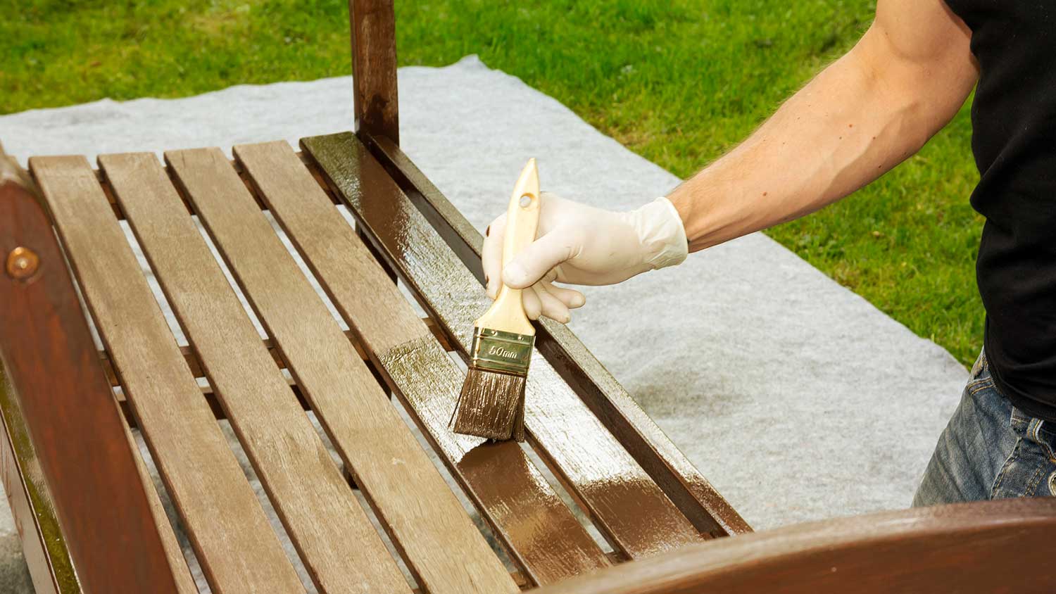 Handyman painting wooden bench with a brush