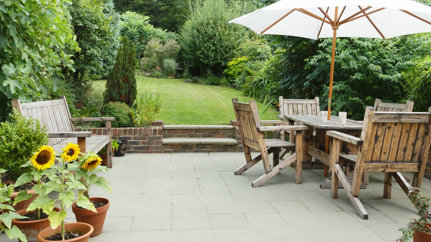 A paved patio with wooden outdoor furniture