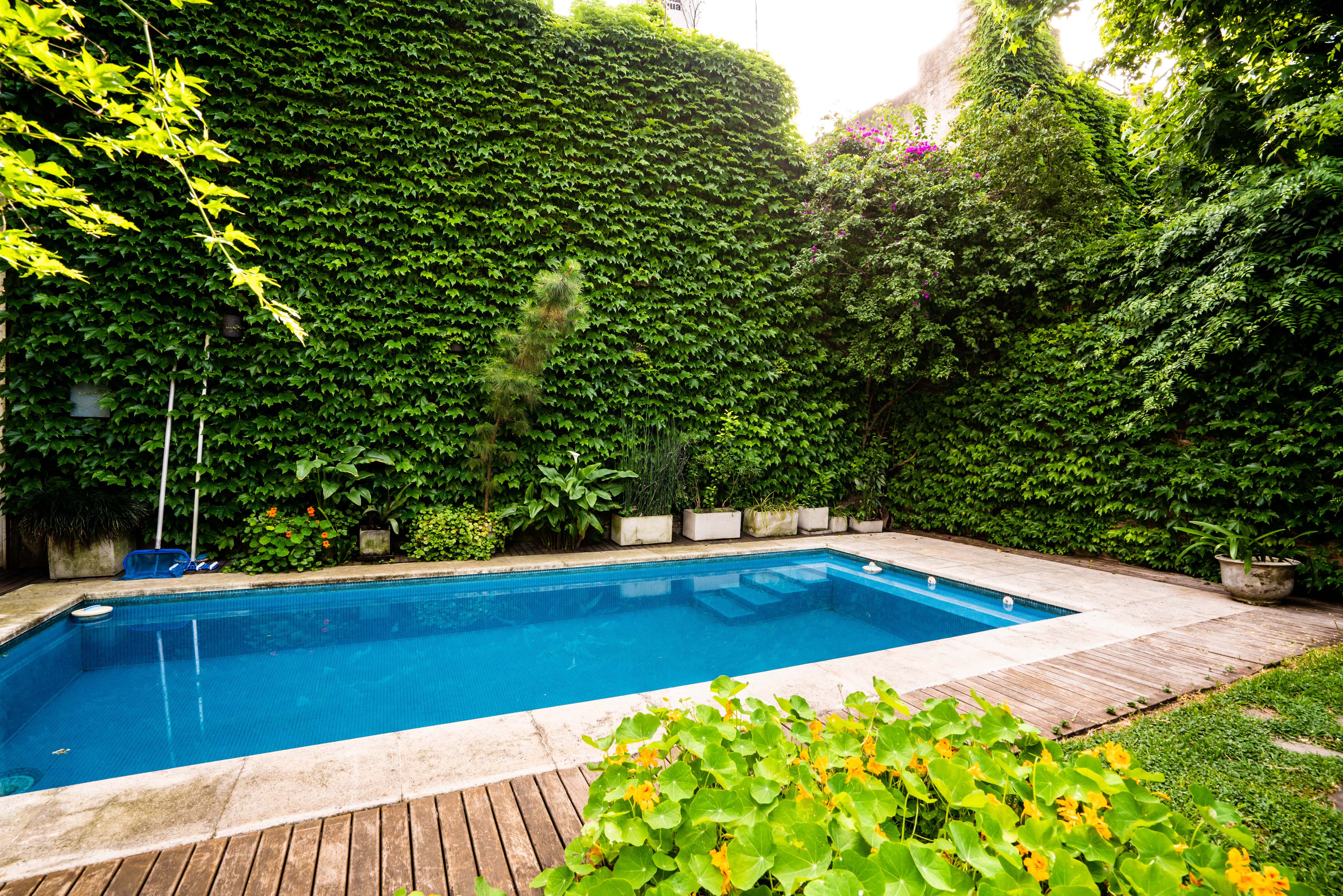 A backyard with an in-ground pool surrounded by a wood platform