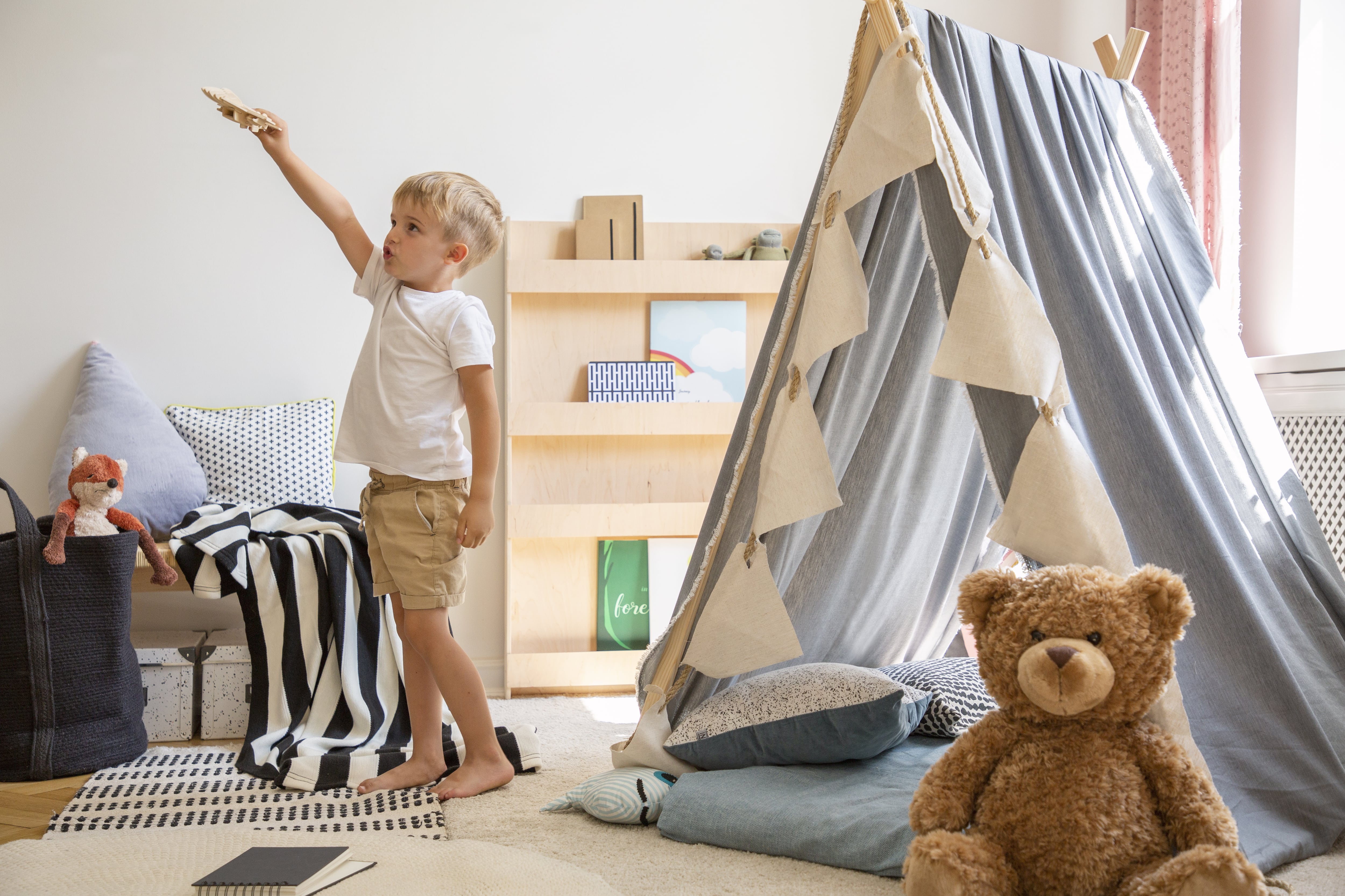 A young kid playing in his room with a play tent